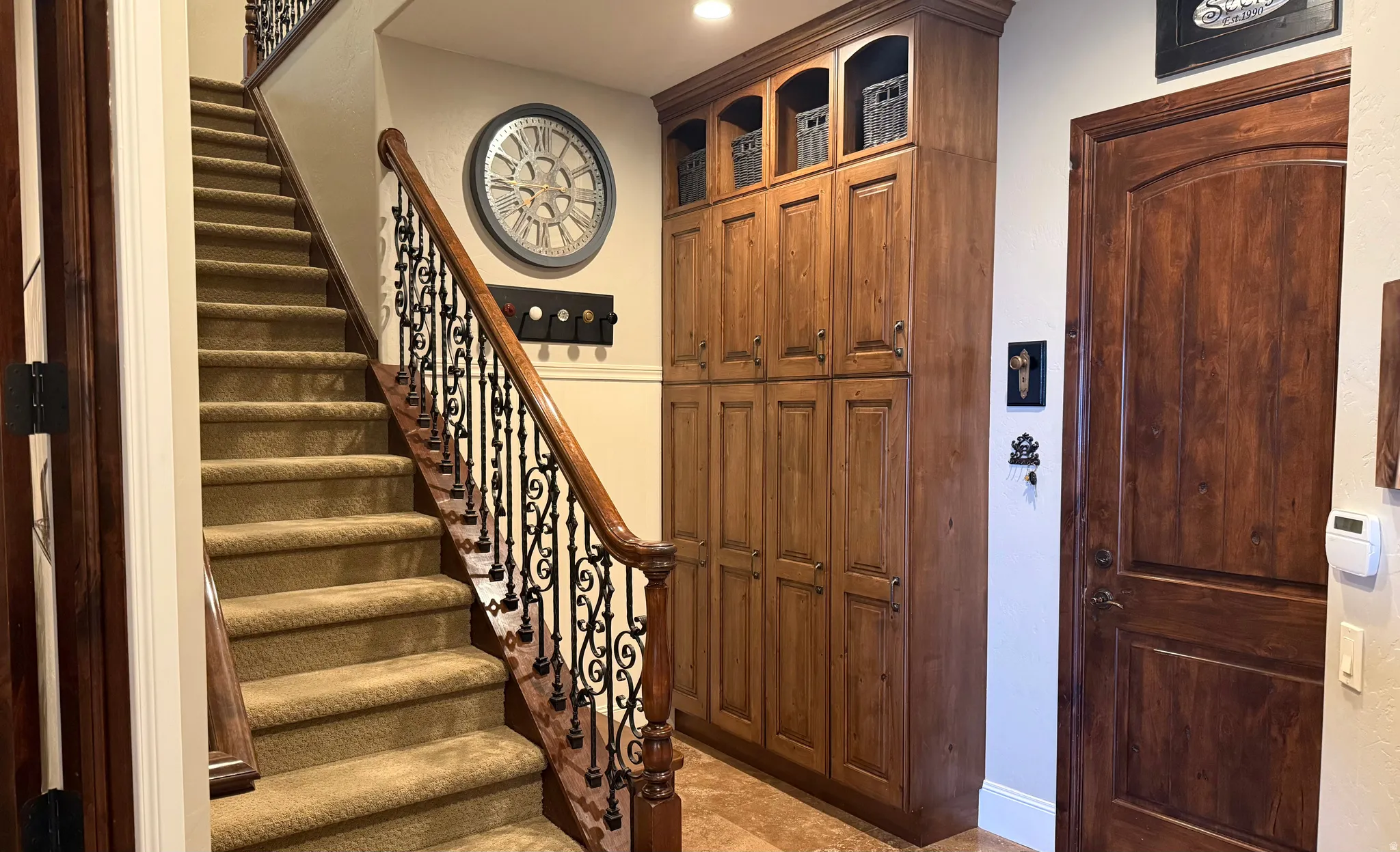 Carpeted staircase with an ornate wrought iron and wood-finish railing