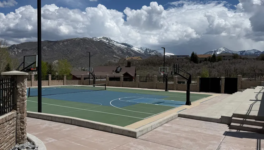 Multi-sport court featuring vibrant blue and green surfacing, basketball hoops, and a tennis net