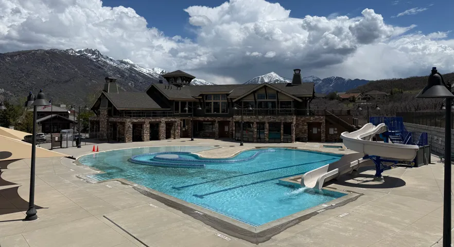 Outdoor swimming pool with integrated water slide, a separate wading area, and extensive concrete decking