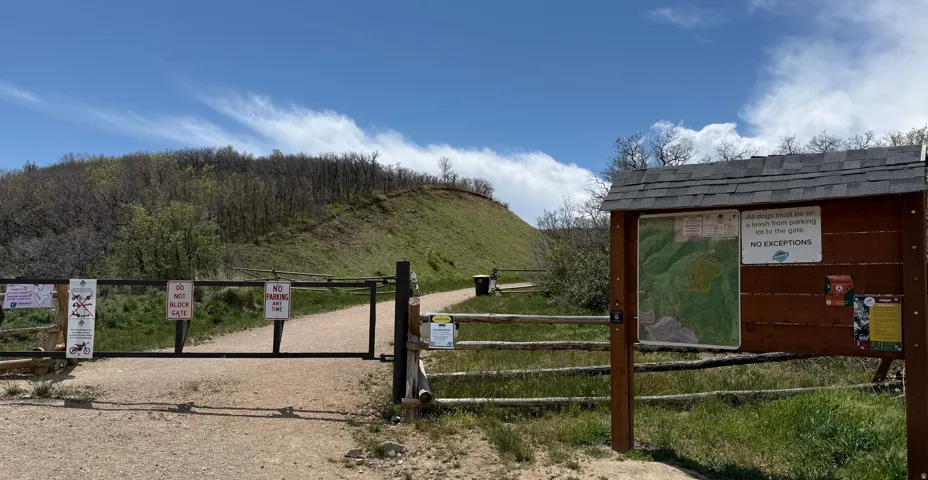 Gated access point featuring a natural wood fence and informational kiosk with shingled roof
