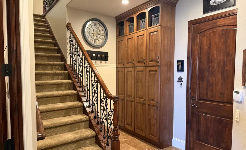 Carpeted staircase with an ornate wrought iron and wood-finish railing