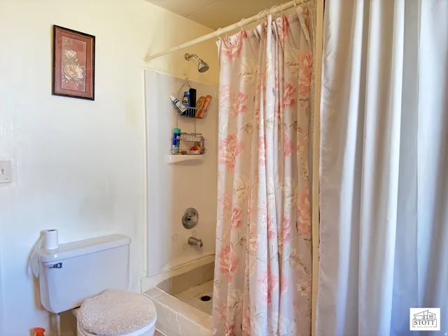 Full bath featuring a shower with shower curtain and toilet