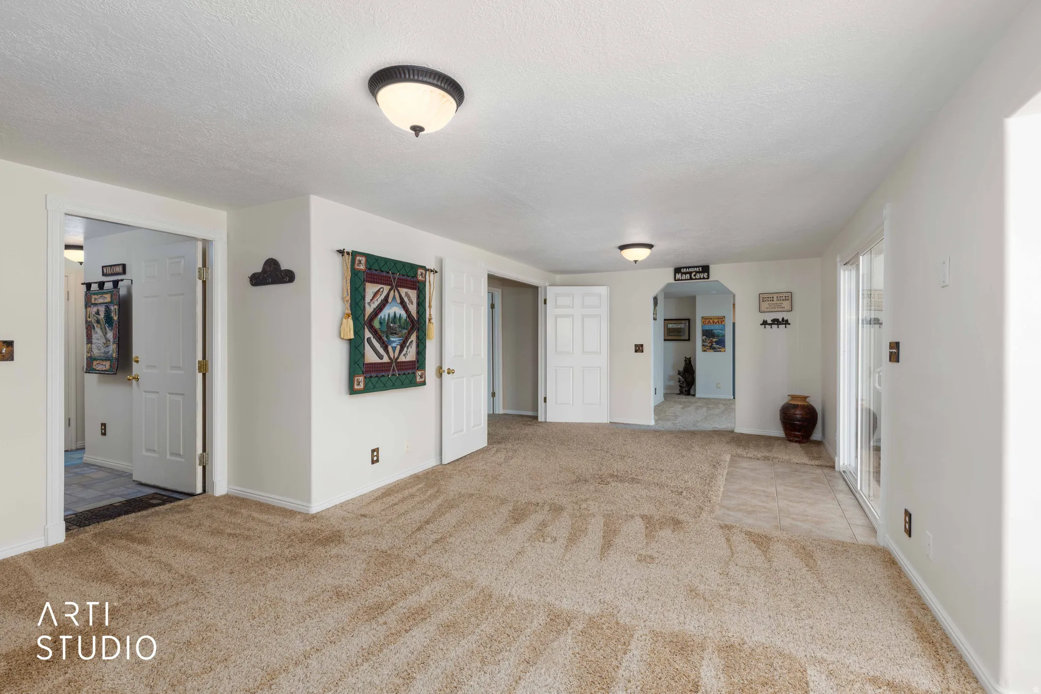 Unfurnished living room with arched walkways, light carpet, and a textured ceiling