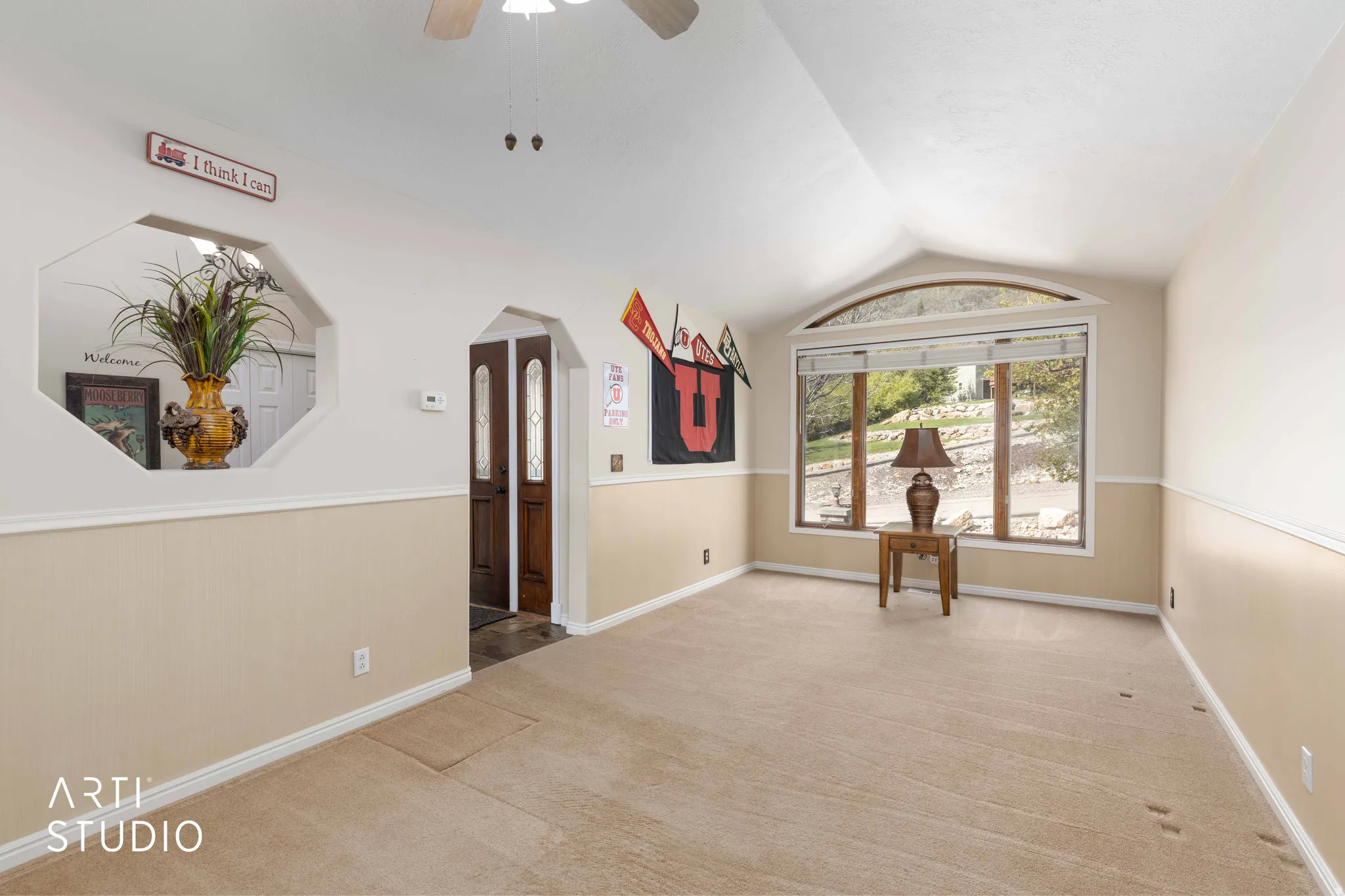 Spare room featuring a ceiling fan, light colored carpet, and arched walkways