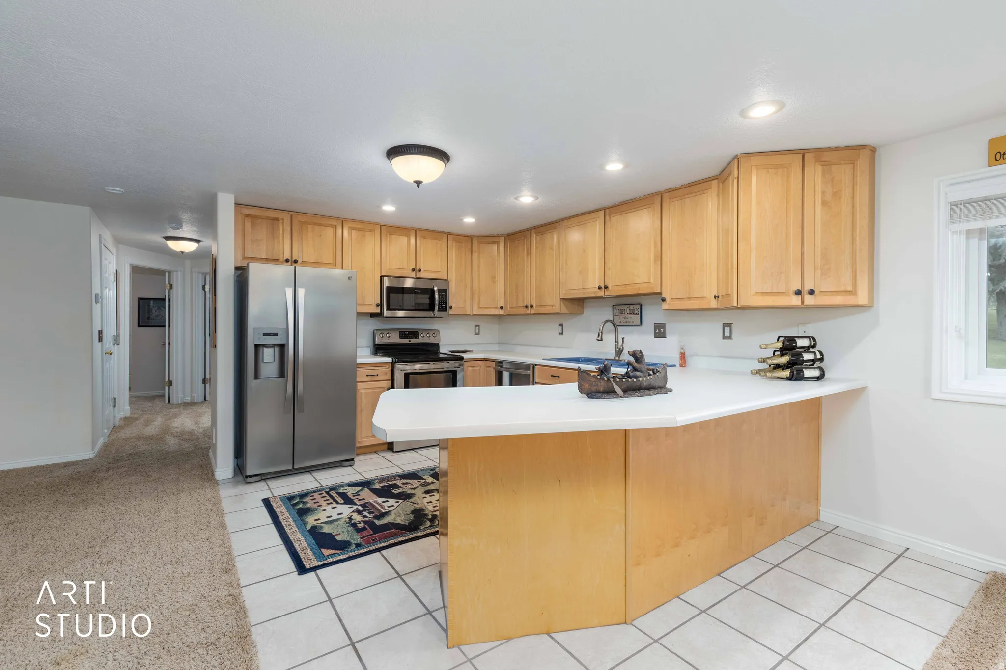 Kitchen featuring light countertops, stainless steel appliances, a peninsula, light tile patterned flooring, and recessed lighting
