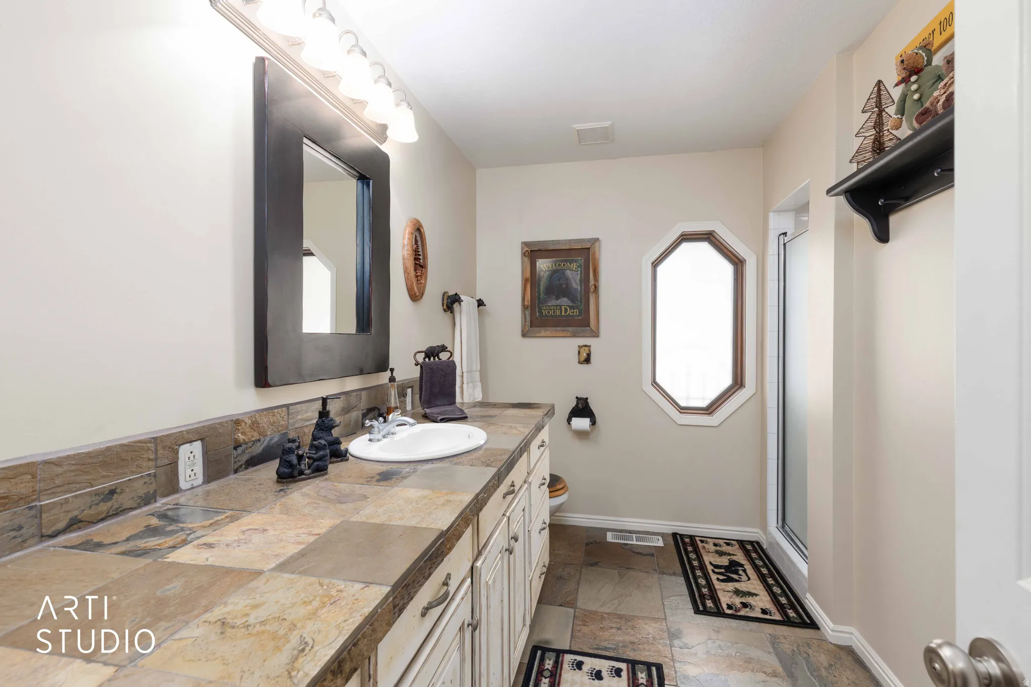 Bathroom featuring vanity, stone tile floors, a shower stall, and healthy amount of natural light