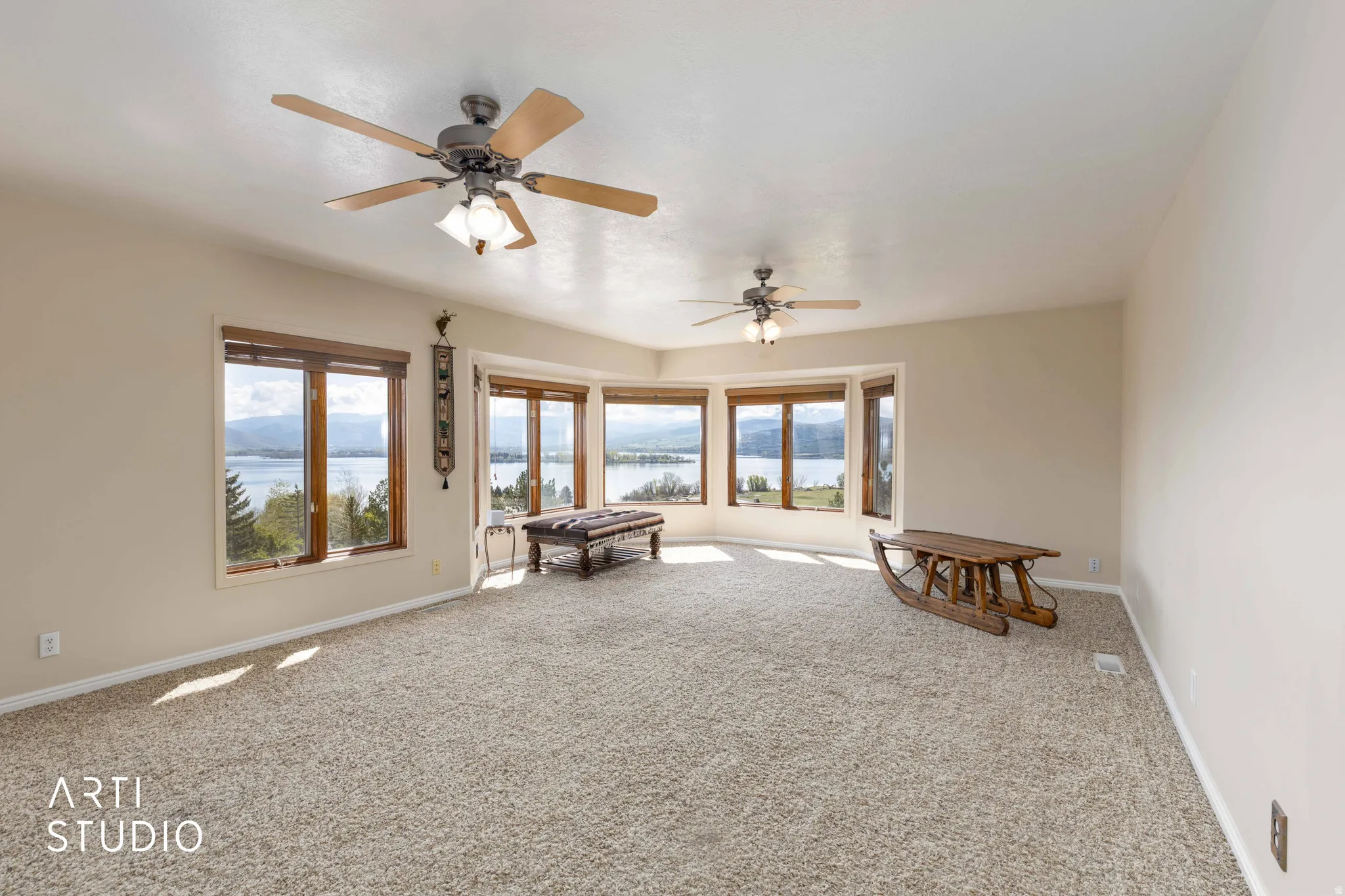 Spare room with a water view, carpet, and a ceiling fan