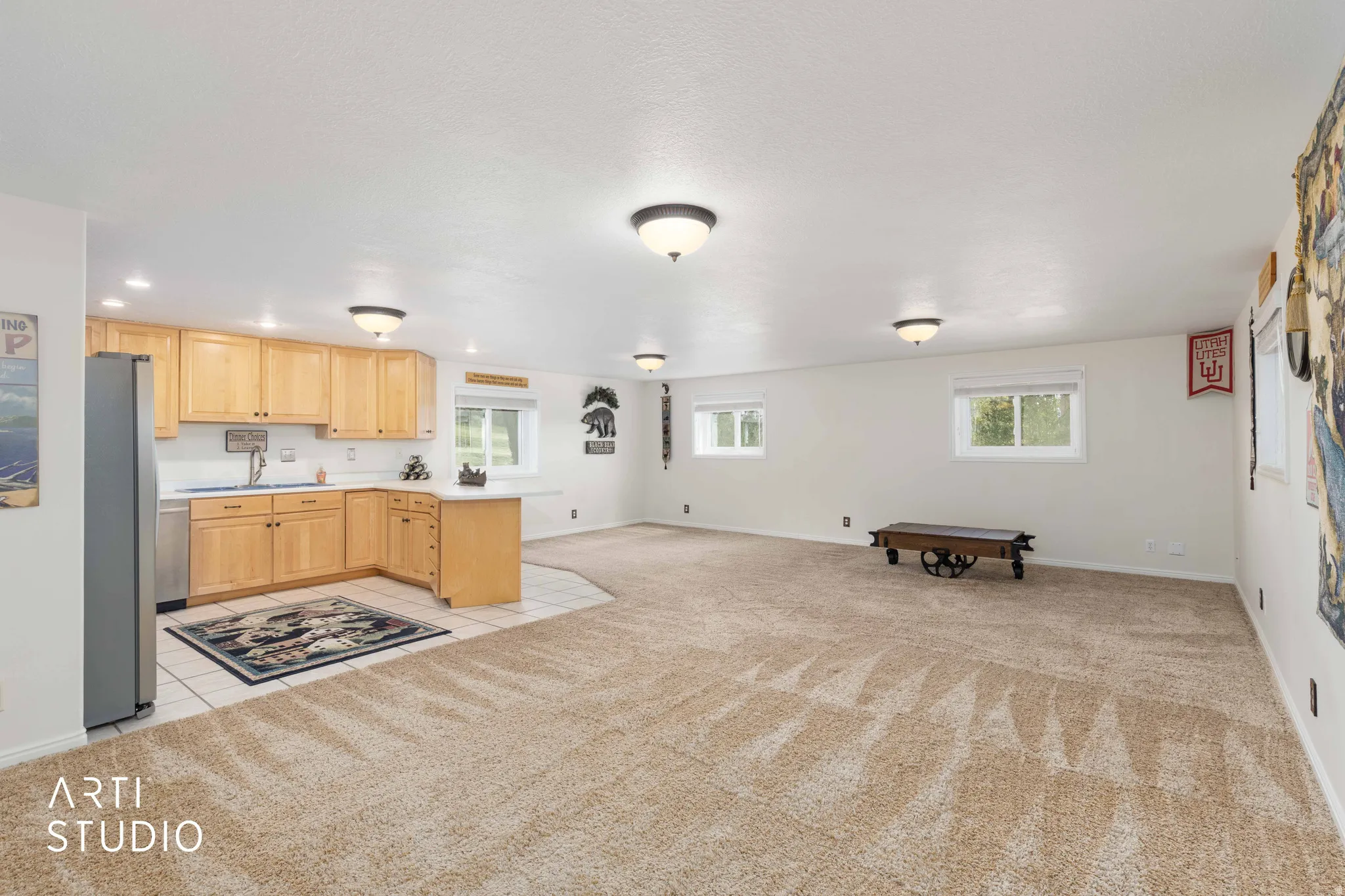 Kitchen featuring light countertops, light wood finish cabinetry, a peninsula, light colored carpet, and plenty of natural light