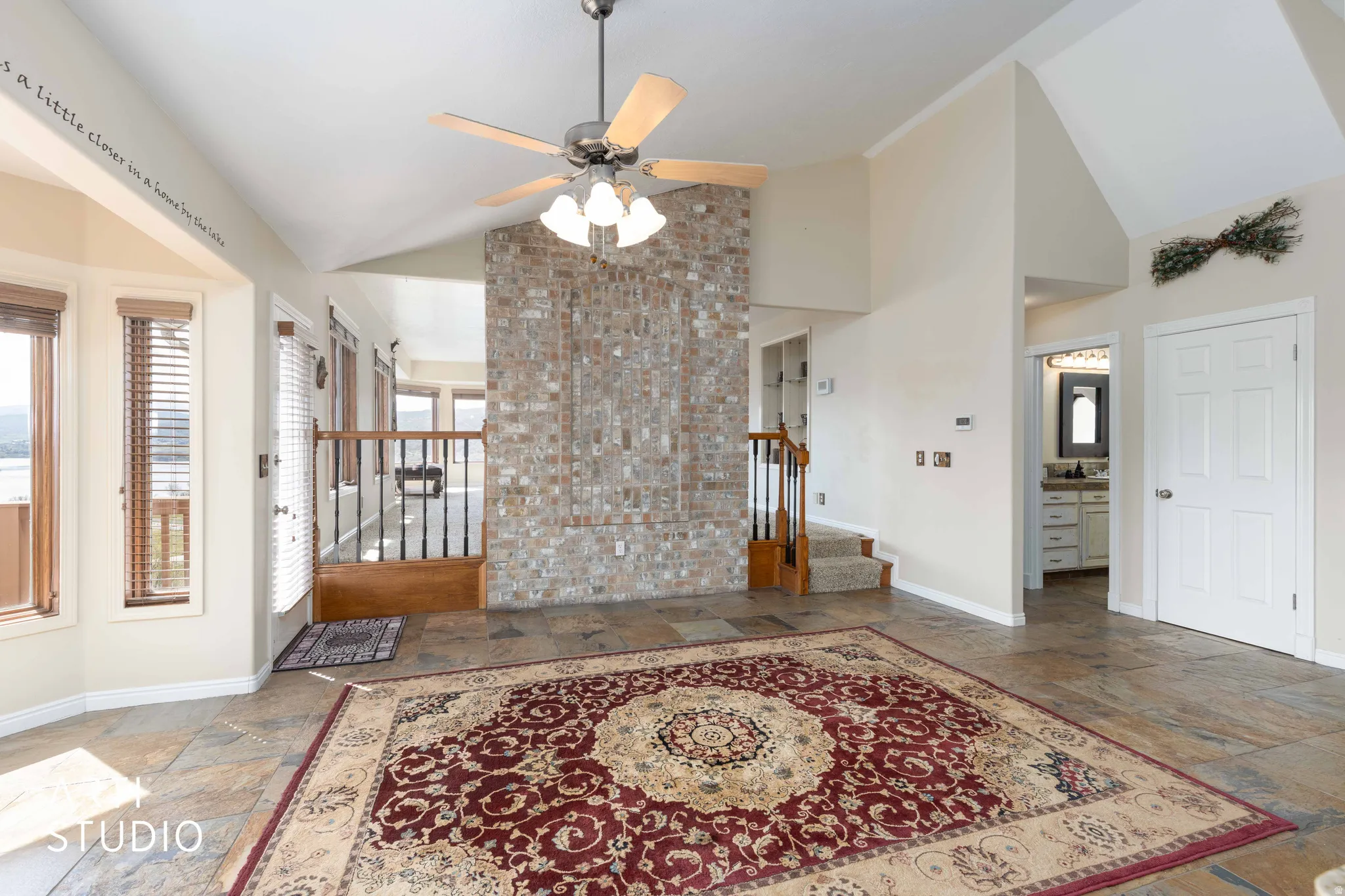 Foyer entrance with stone tile floors, vaulted ceiling, and a ceiling fan
