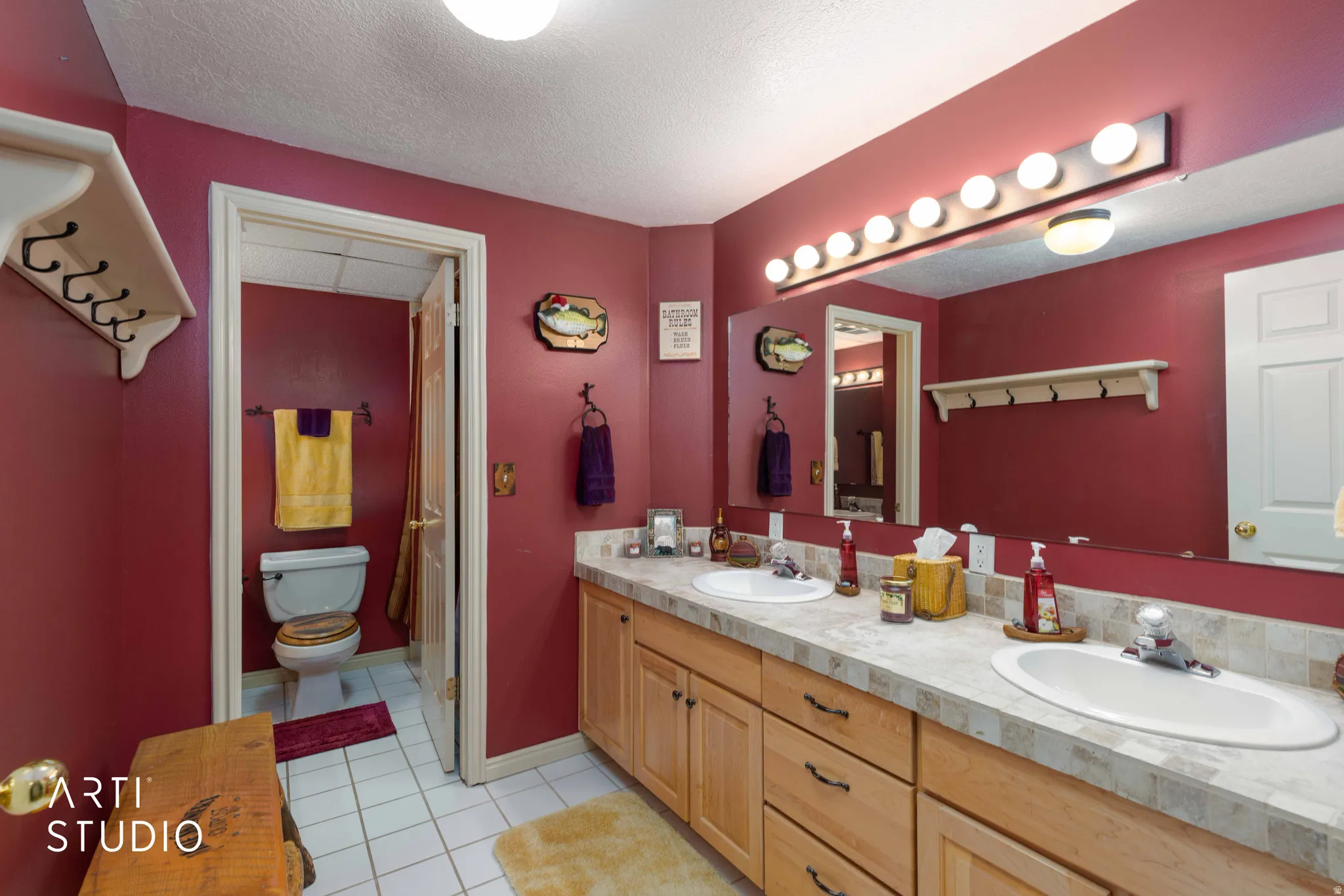 Bathroom with double vanity, a textured ceiling, and light tile patterned flooring