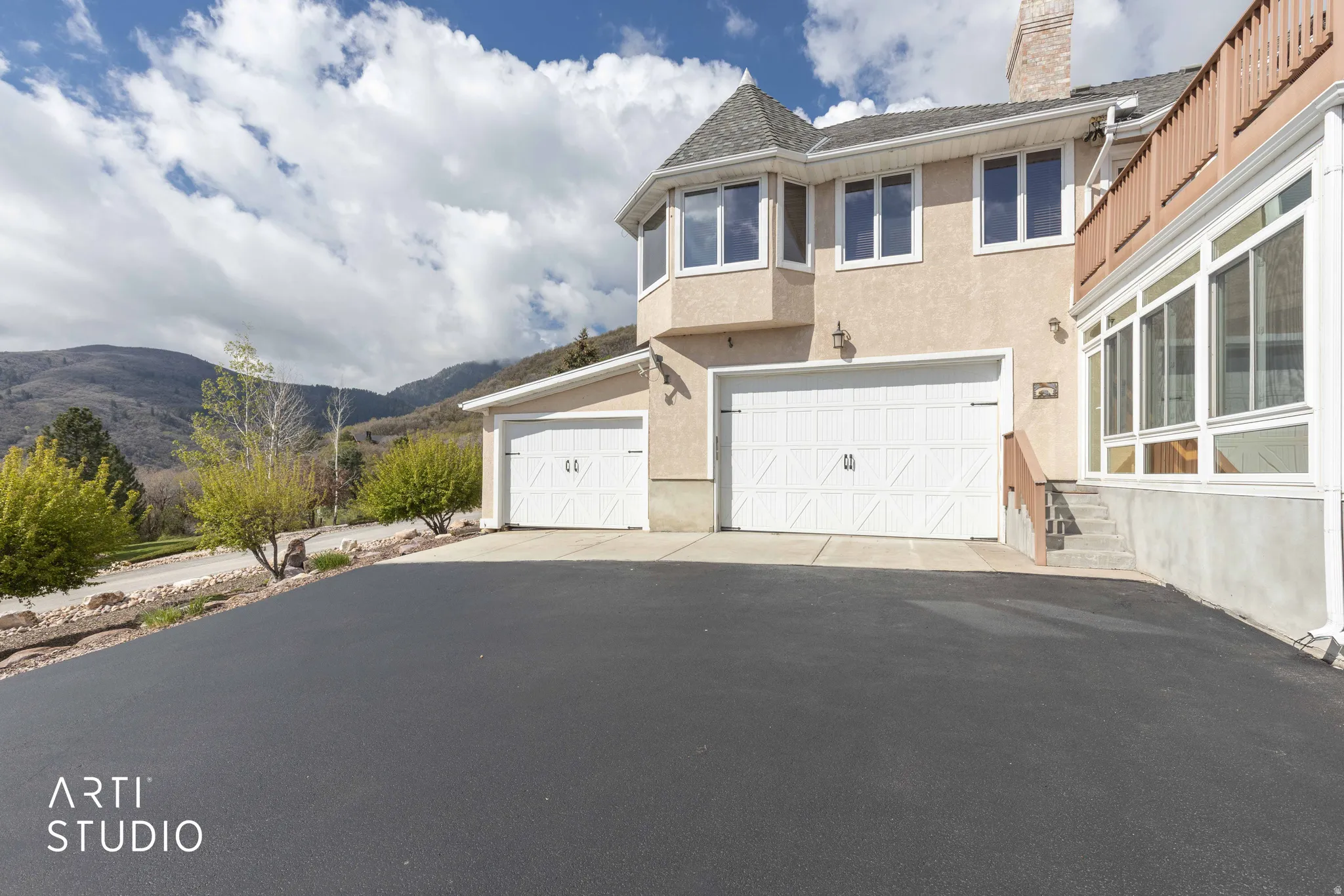 View of front of property with stucco siding, a mountain view, a garage, a chimney, and driveway