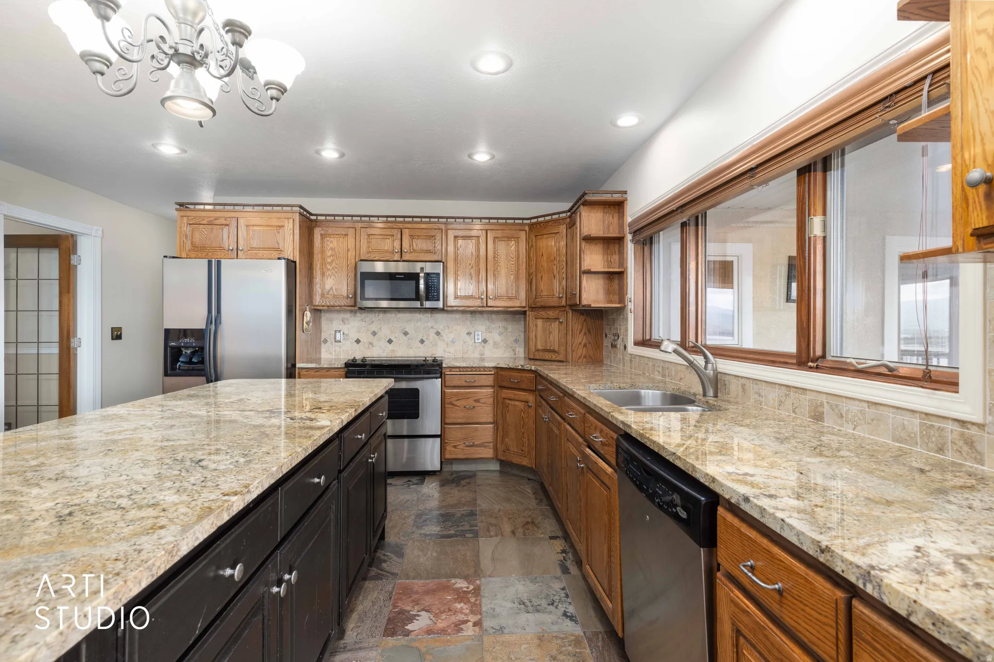 Kitchen featuring open shelves, stainless steel appliances, and light stone countertops