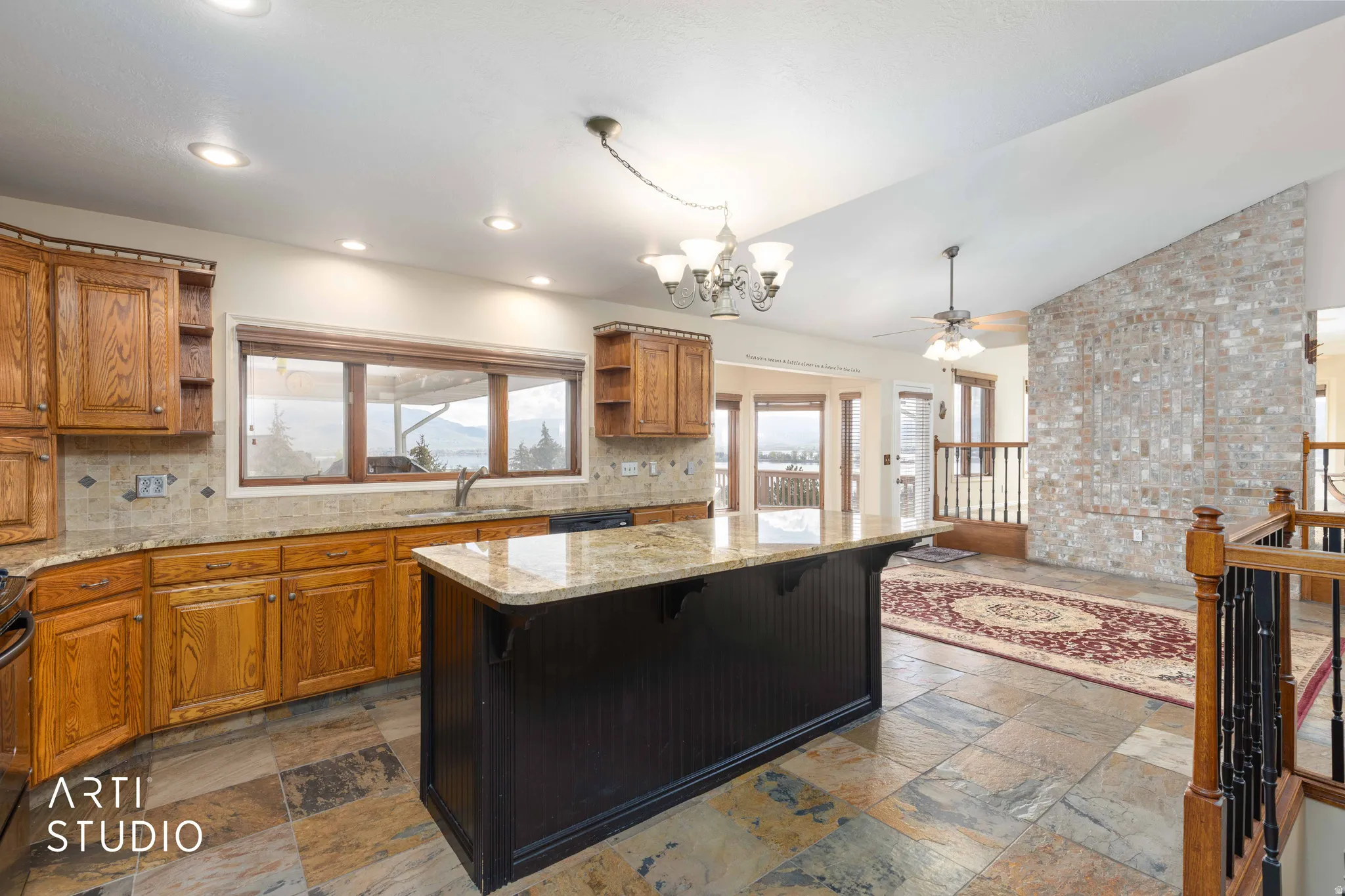 Kitchen with open shelves, a chandelier, a kitchen breakfast bar, wood finish cabinetry, and lofted ceiling