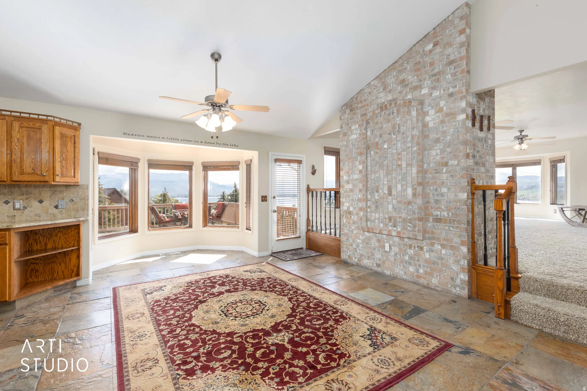 Foyer entrance with a ceiling fan, stone tile flooring, and lofted ceiling