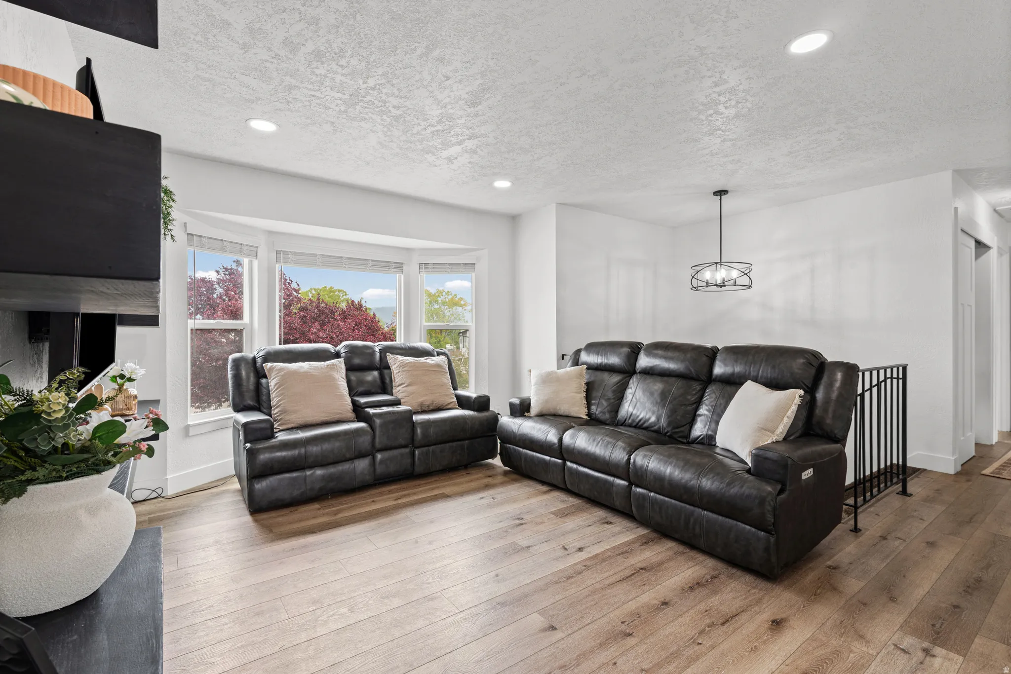 Living room featuring hardwood / wood-style flooring, a textured ceiling, and suspended lighting