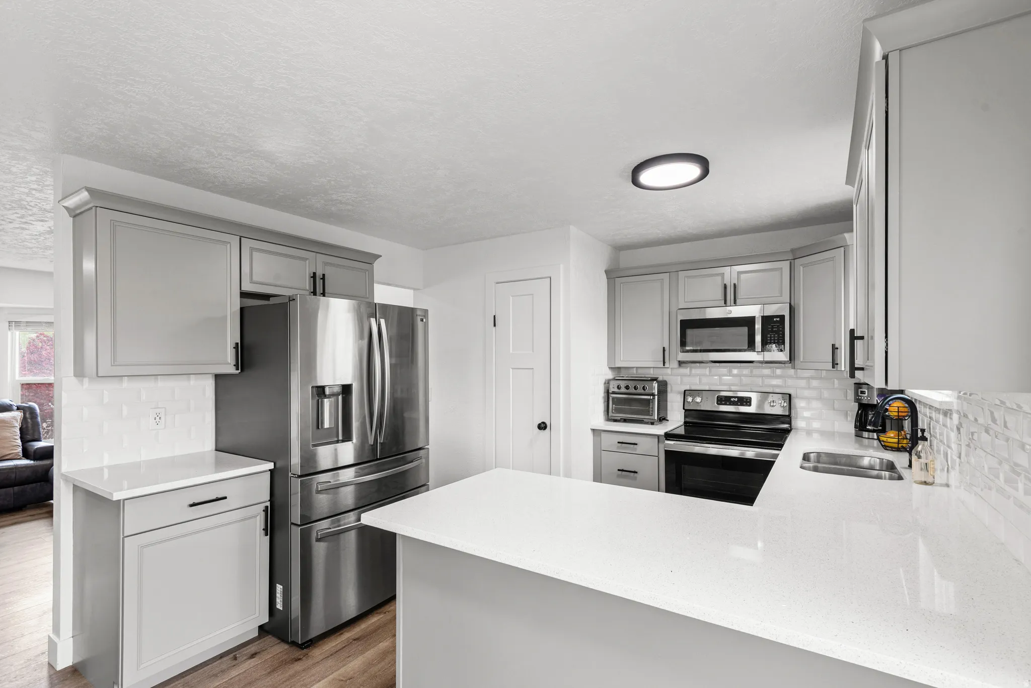 Kitchen featuring tasteful backsplash, gray cabinetry, stainless steel appliances, a peninsula, and a textured ceiling