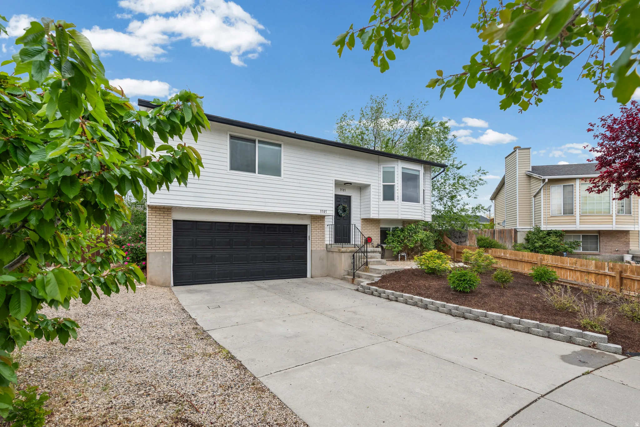 Raised ranch featuring brick siding, driveway, and a garage