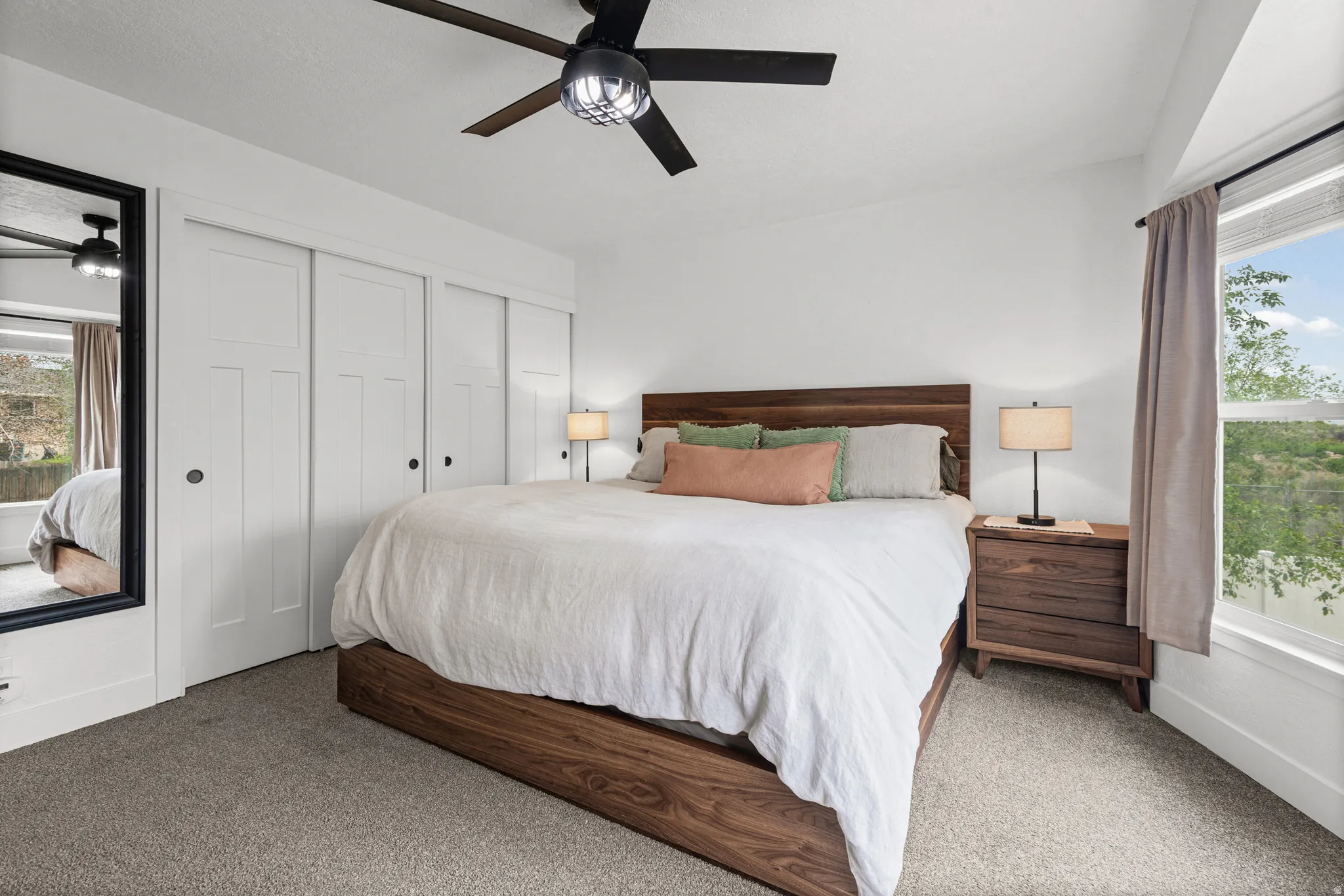 Carpeted bedroom with multiple windows, multiple closets, and ceiling fan