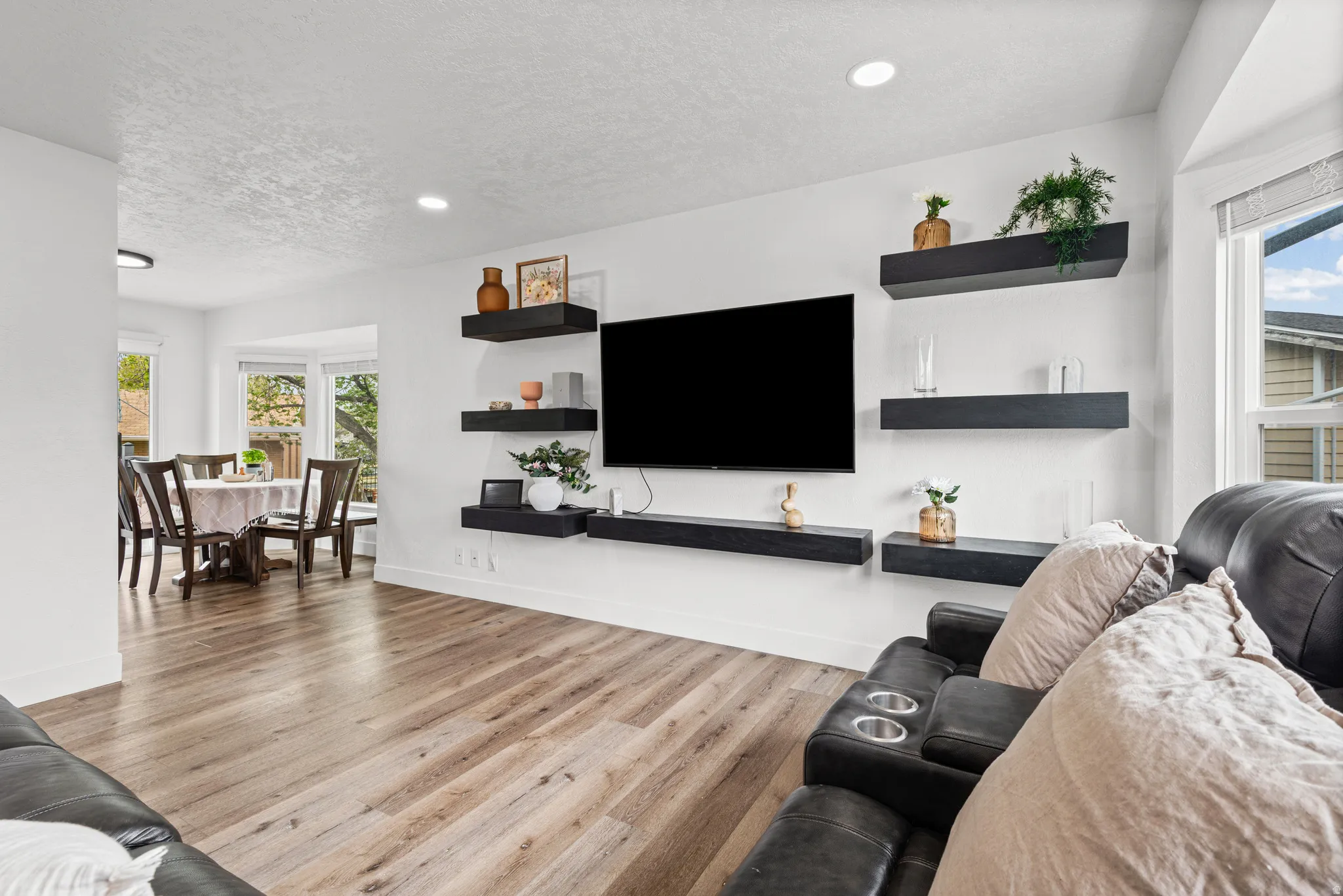 Living area featuring light wood-style floors, a textured ceiling, and recessed lighting