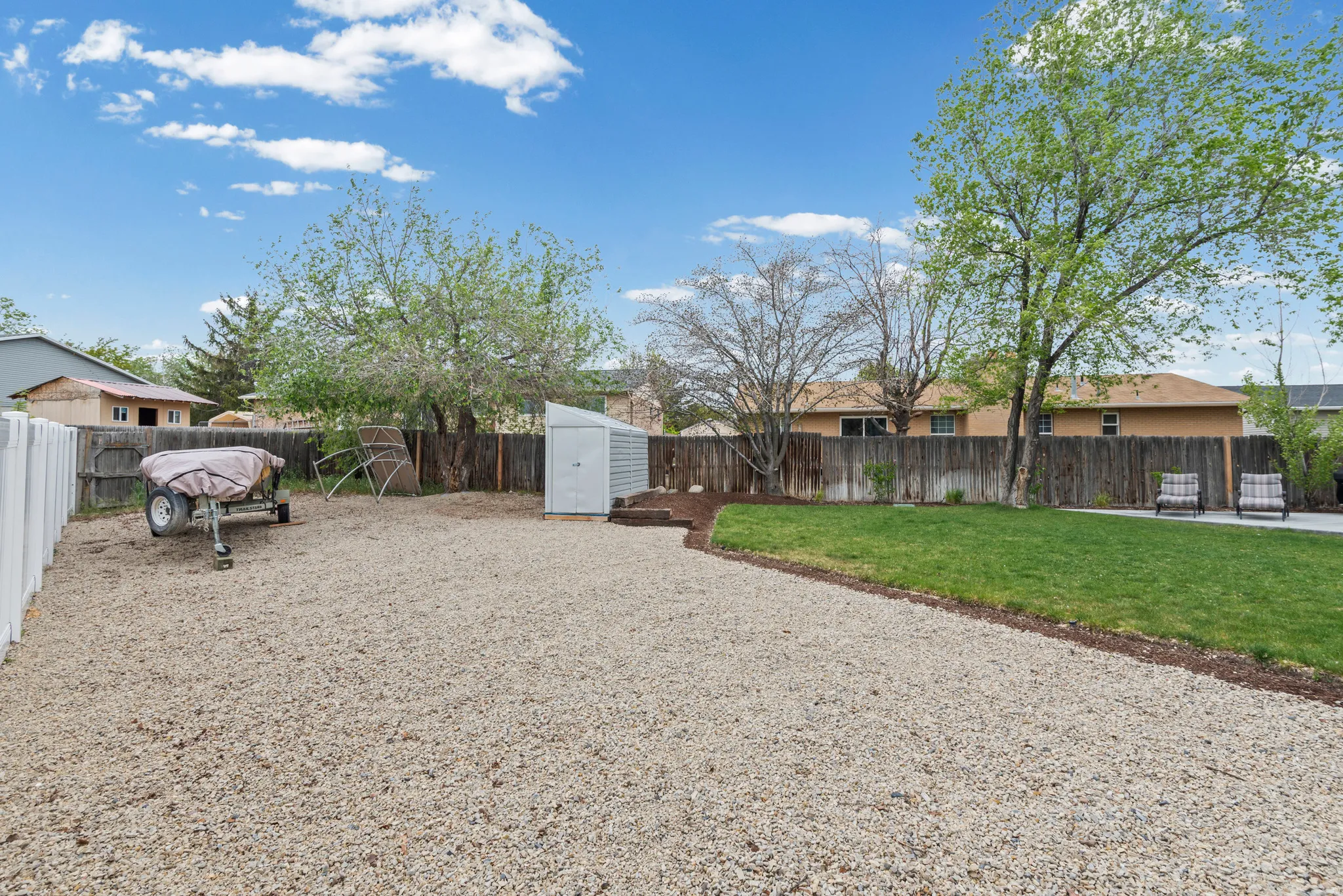 Fenced backyard featuring a storage unit
