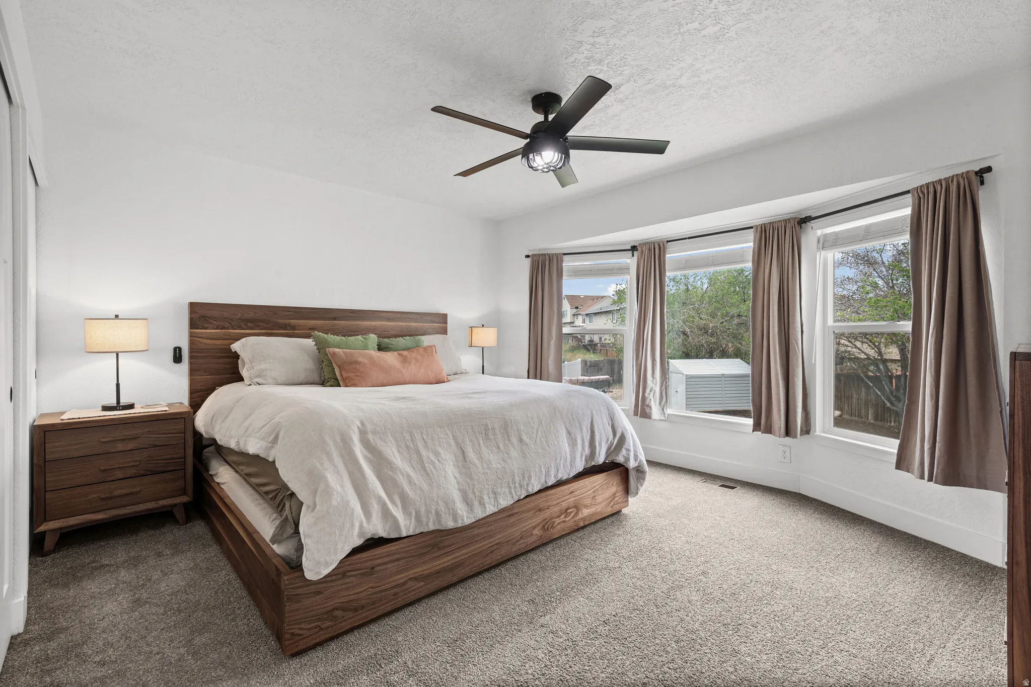 Carpeted bedroom with ceiling fan and a textured ceiling