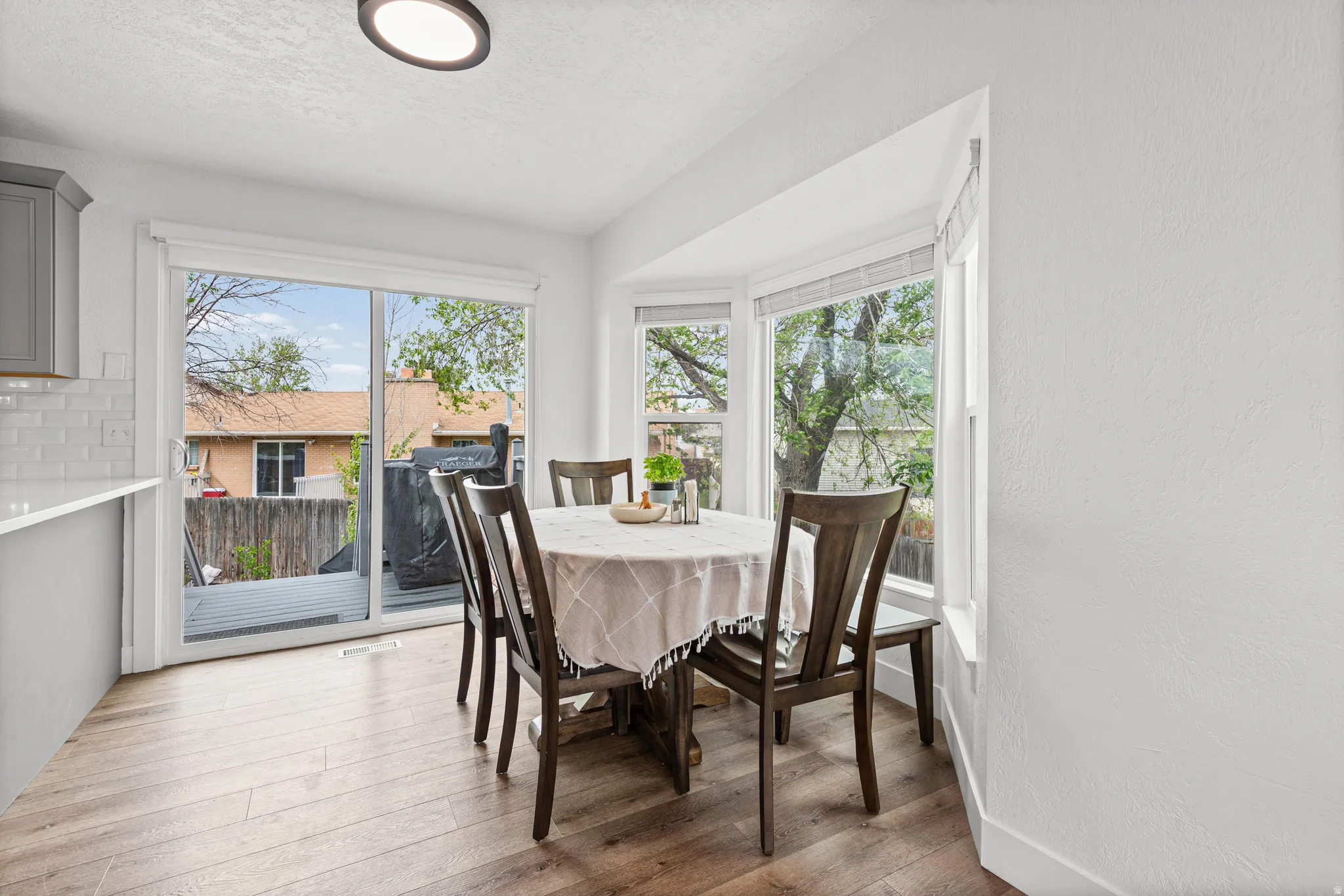 Dining space featuring hardwood / wood-style floors, plenty of natural light, a textured wall, and a textured ceiling