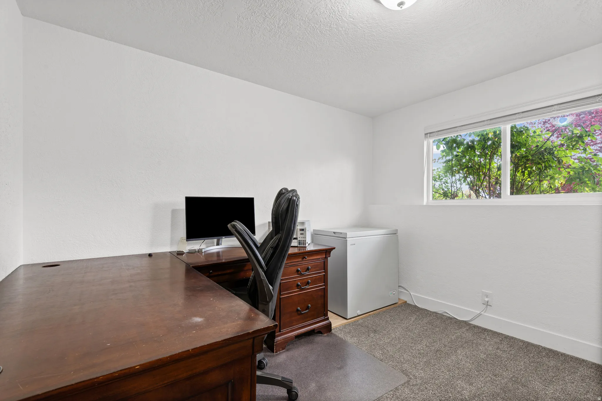 Office space with light carpet and a textured ceiling