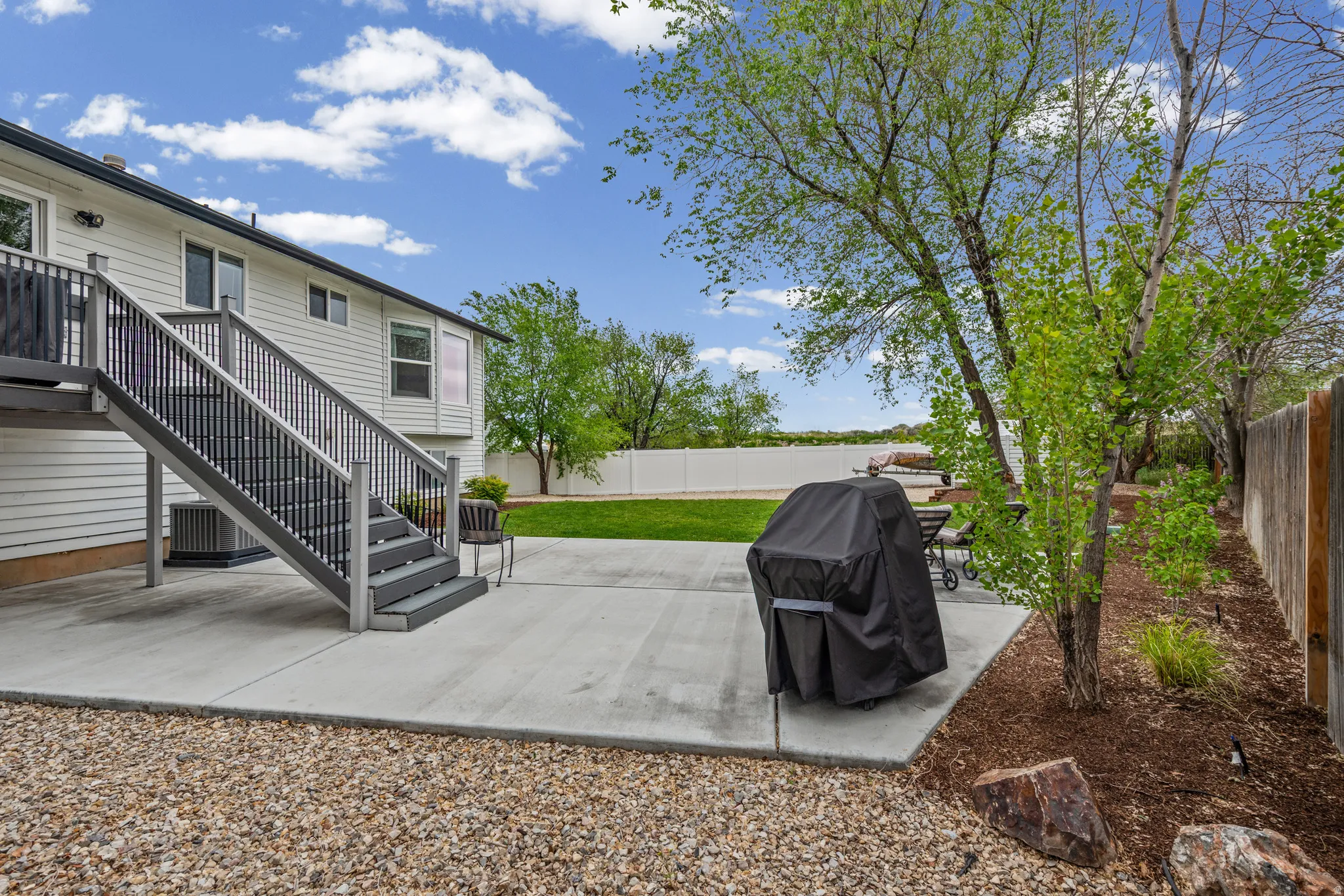 Fenced backyard featuring a patio and a grill