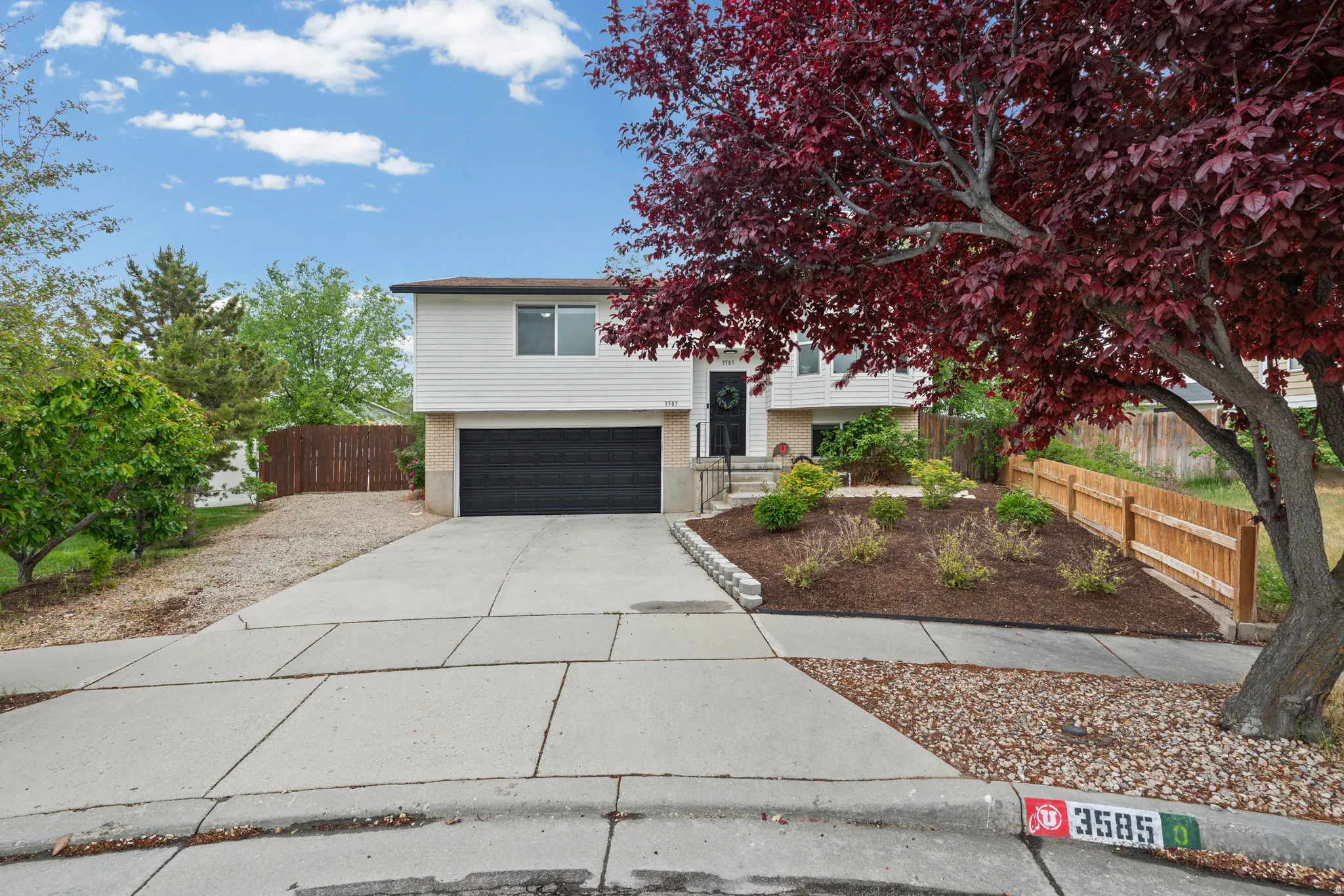 Split foyer home featuring concrete driveway, an attached garage, and brick siding
