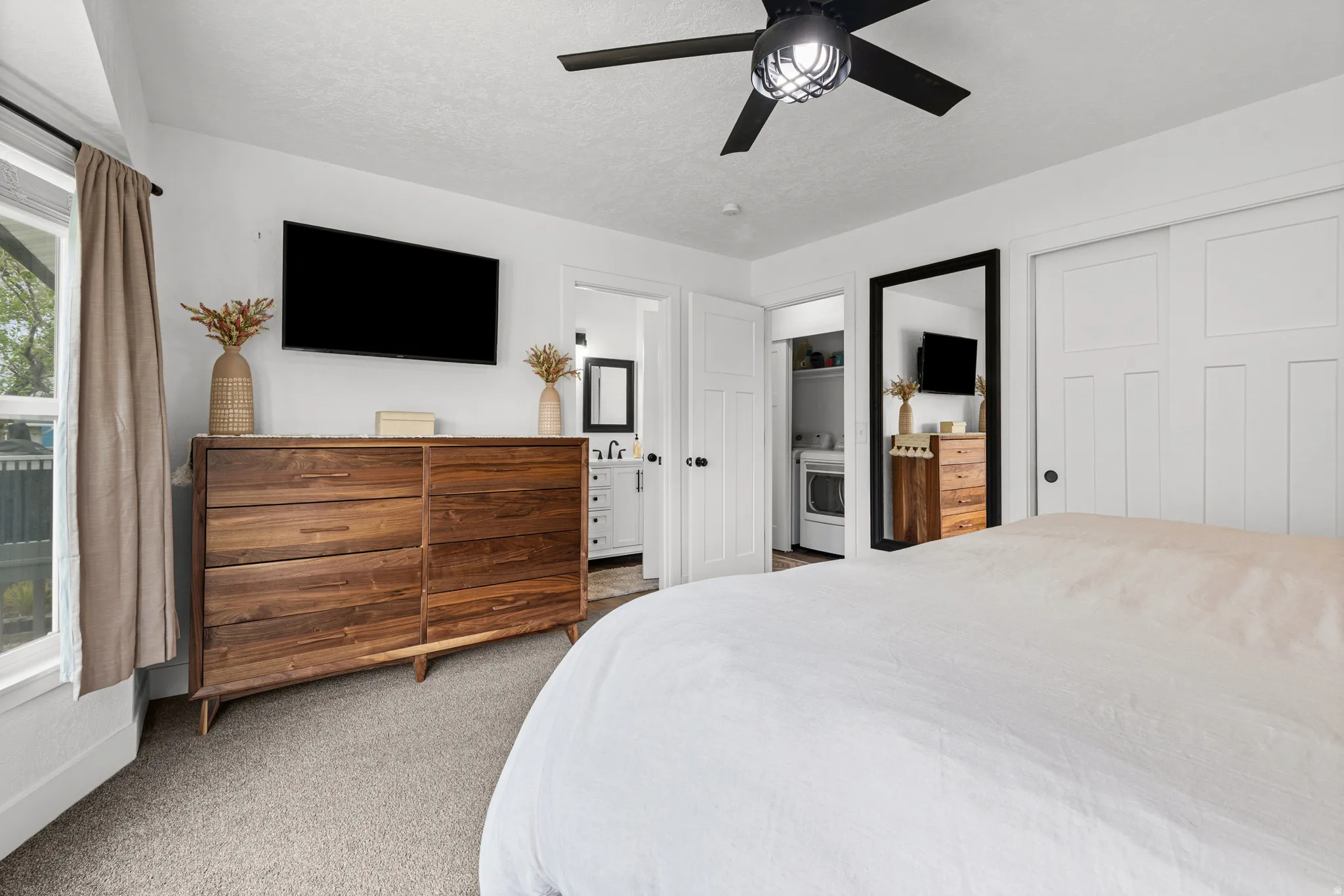 Bedroom with light colored carpet, ceiling fan, a closet, washer / dryer, and a textured ceiling