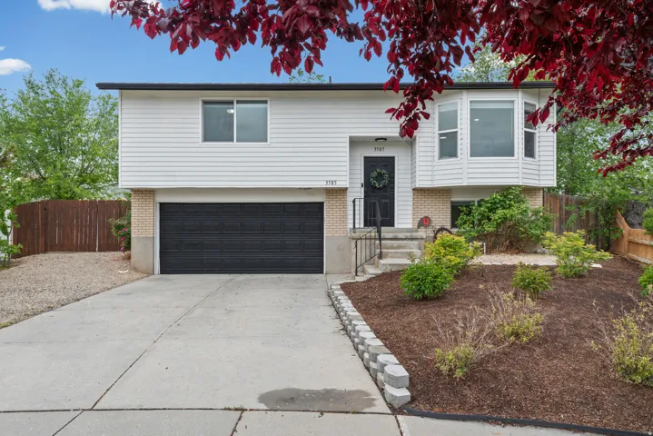 Raised ranch featuring brick siding, concrete driveway, and a garage