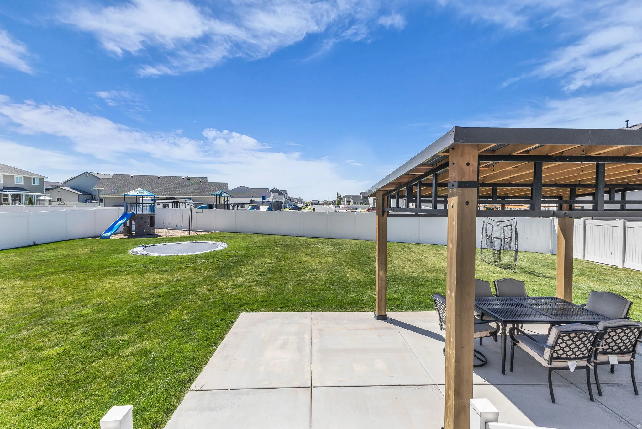 Fenced backyard featuring a playground, a residential view, outdoor dining space, and a patio area