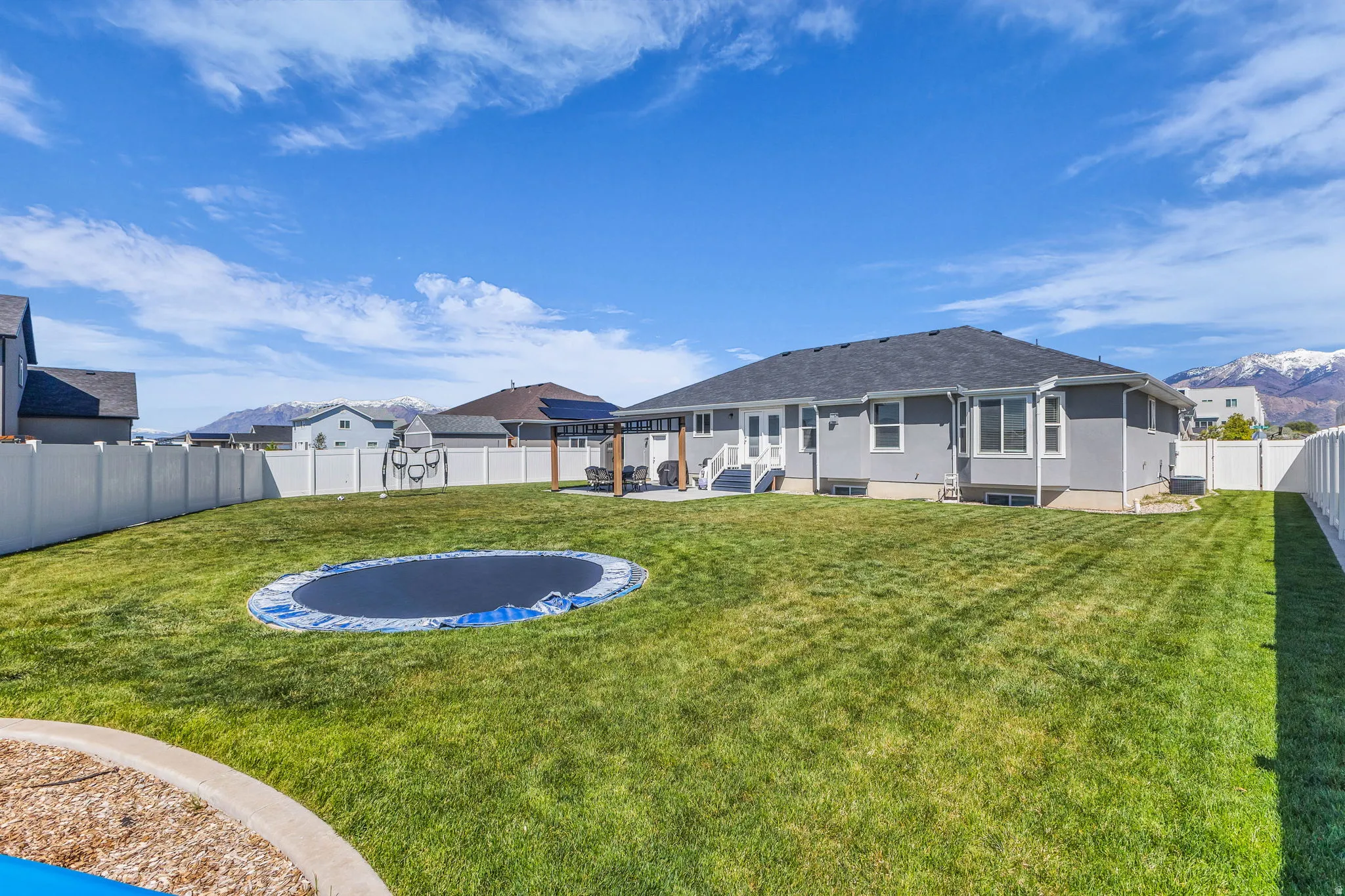 Back of property featuring a fenced backyard, a mountain view, stucco siding, and a patio