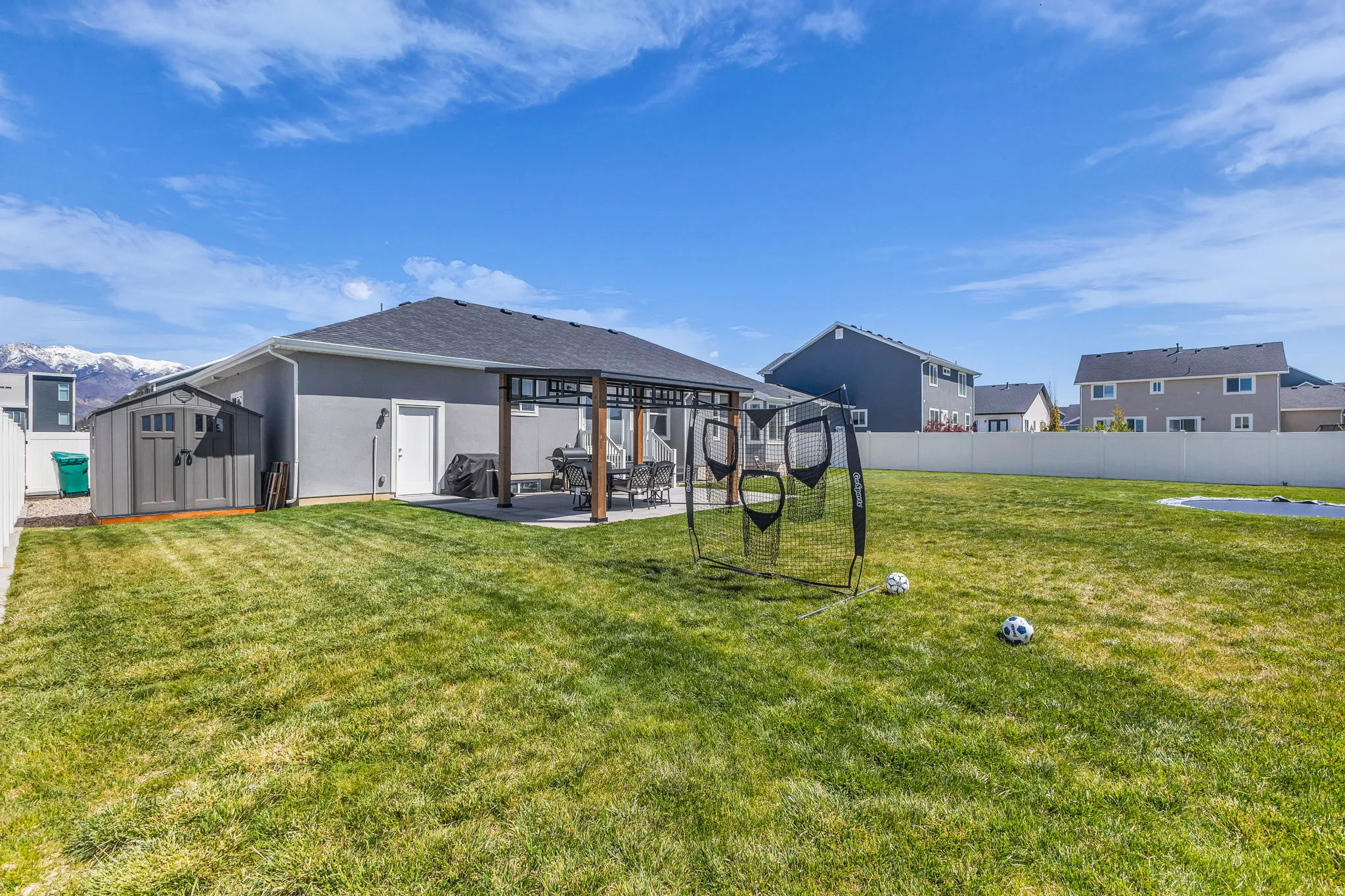 Back of house with a storage unit, stucco siding, a patio area, a fenced backyard, and a pergola