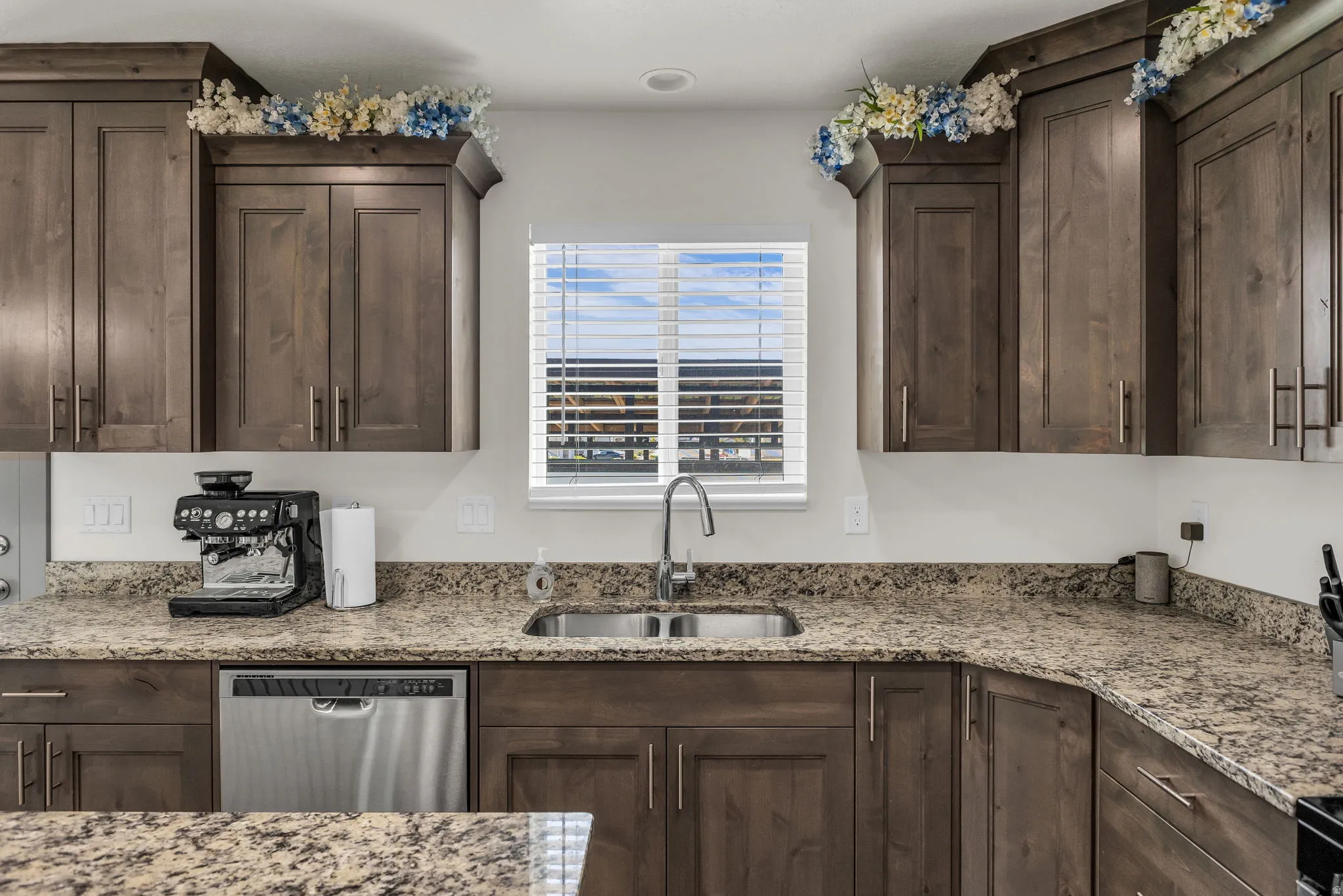 Kitchen with dark wood finish cabinetry, light stone counters, and dishwasher