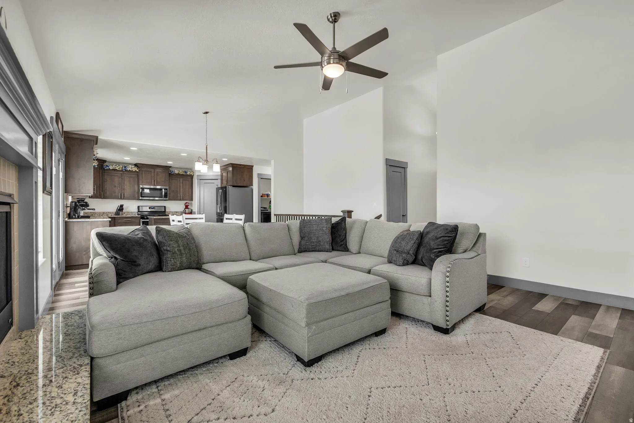 Living room featuring hanging lights, ceiling fan, lofted ceiling, and light wood-type flooring
