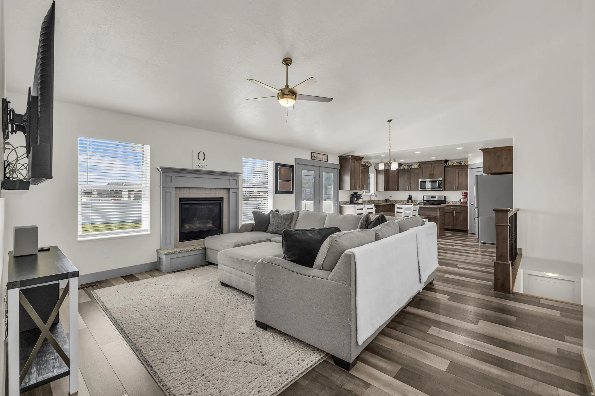 Living area featuring dark wood-type flooring, ceiling fan, a chandelier, a glass covered fireplace, and vaulted ceiling