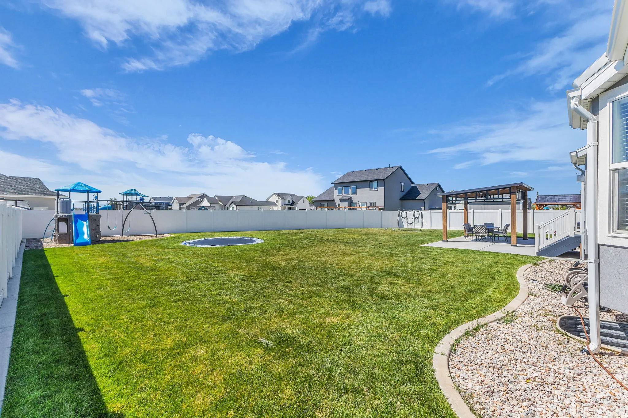 Fenced backyard featuring a residential view, a patio, and a playground