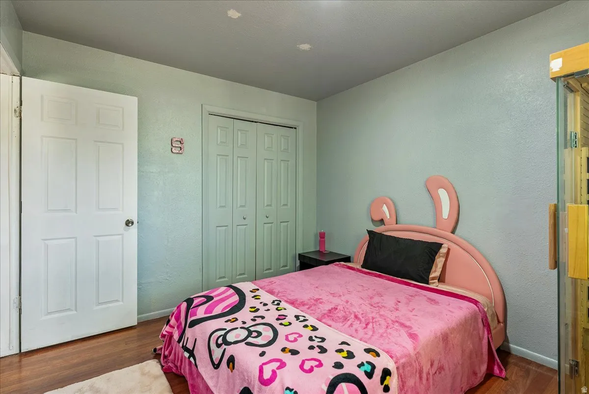 Bedroom with wood finished floors, a closet, and a textured wall