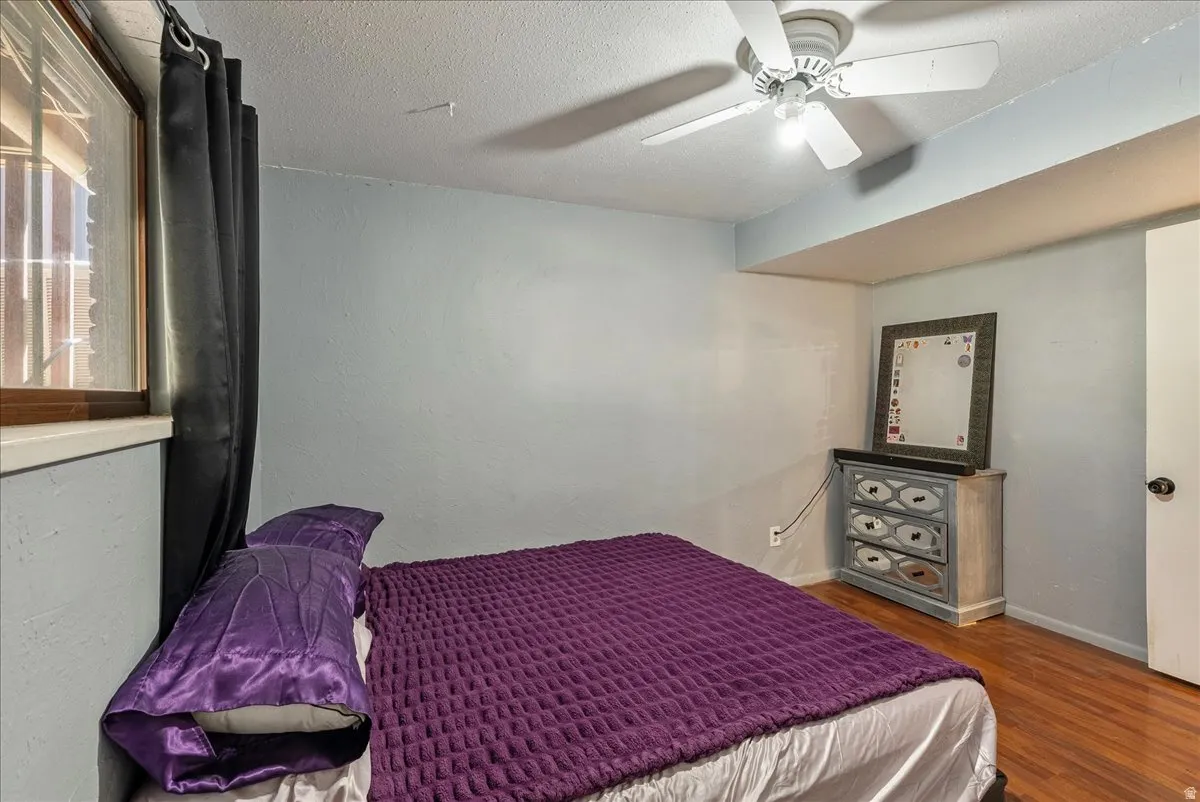 Bedroom with a textured ceiling, ceiling fan, and wood finished floors