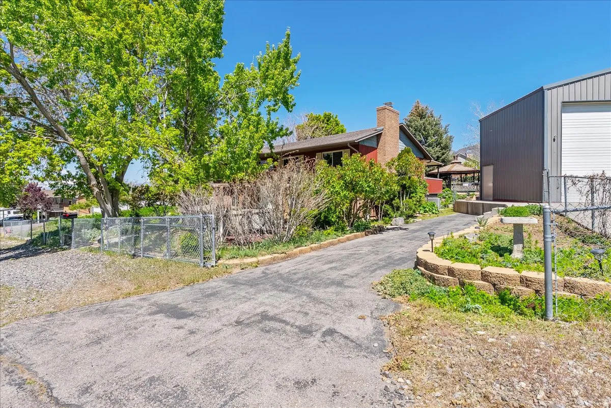 View of side of home featuring a chimney and a gate