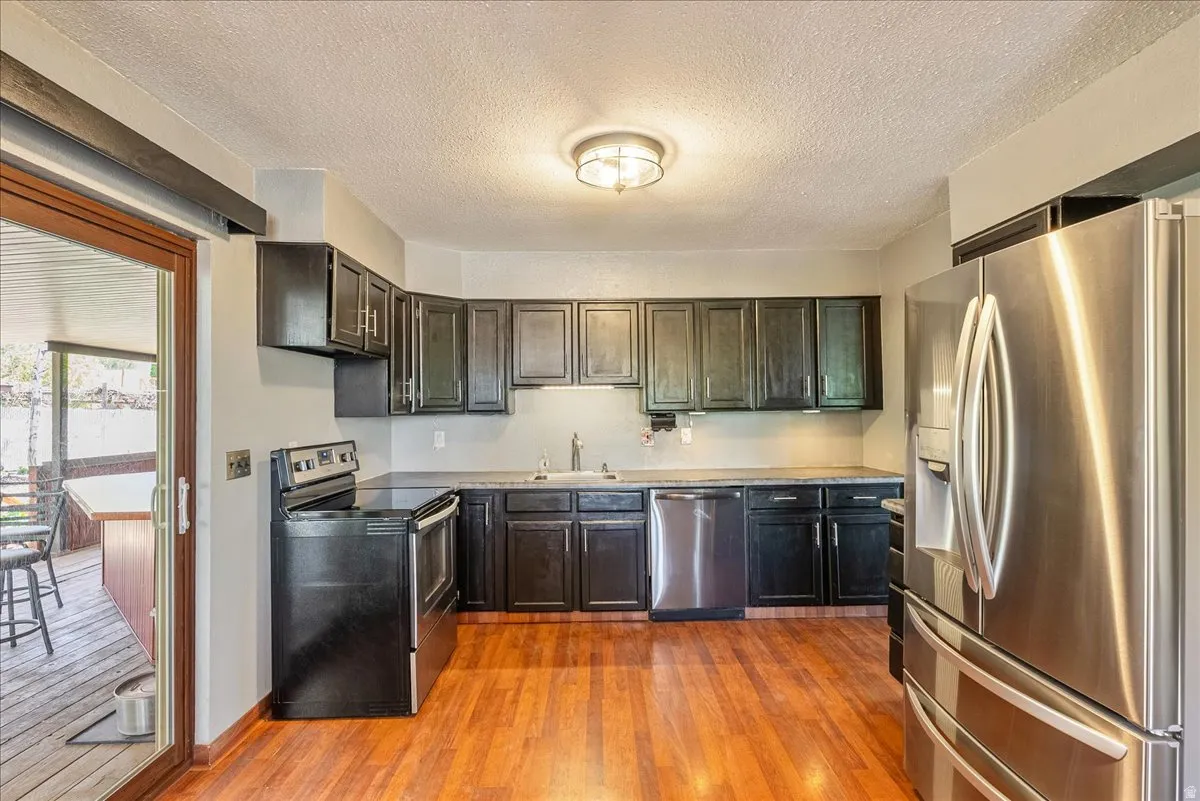 Kitchen featuring stainless steel appliances, light wood-type flooring, a textured ceiling, and light countertops