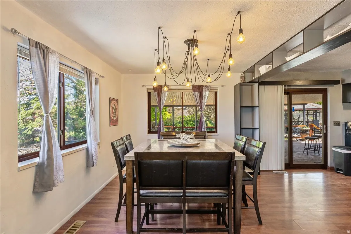 Dining space featuring dark wood finished floors, suspended lighting, and a textured ceiling