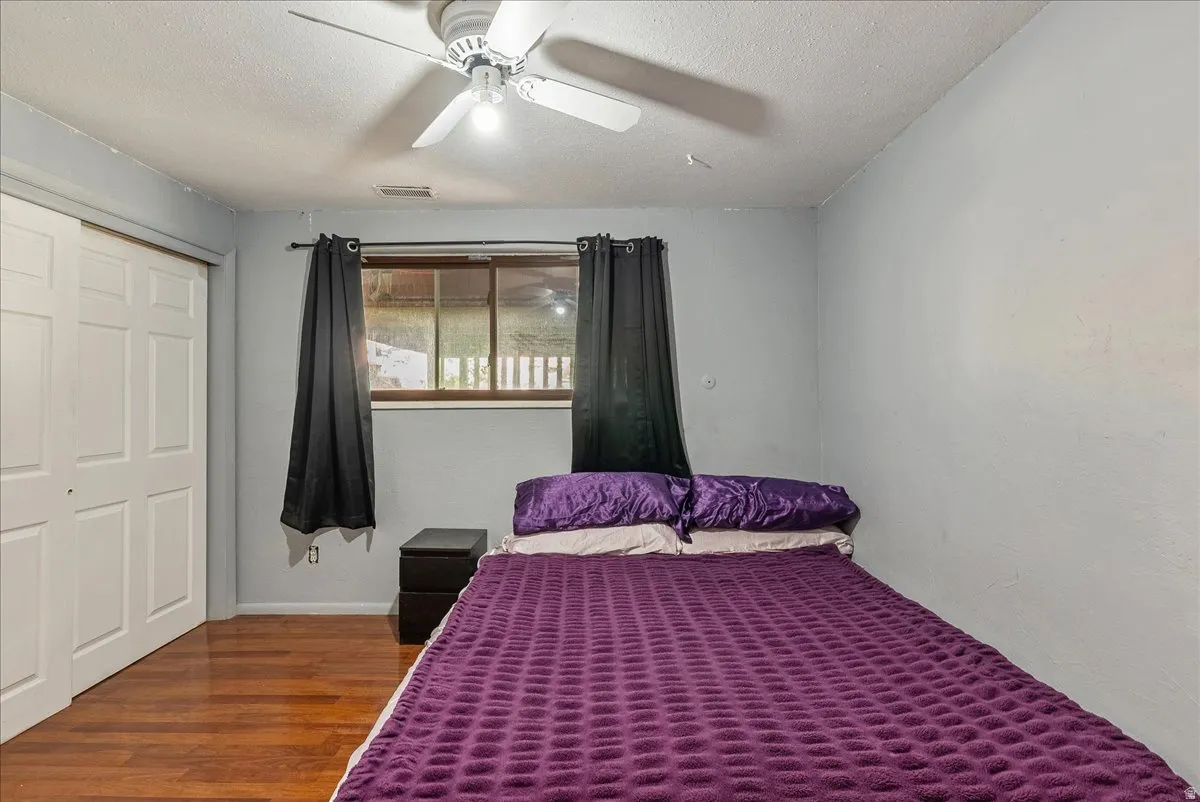 Bedroom featuring a closet, wood finished floors, a textured ceiling, and ceiling fan