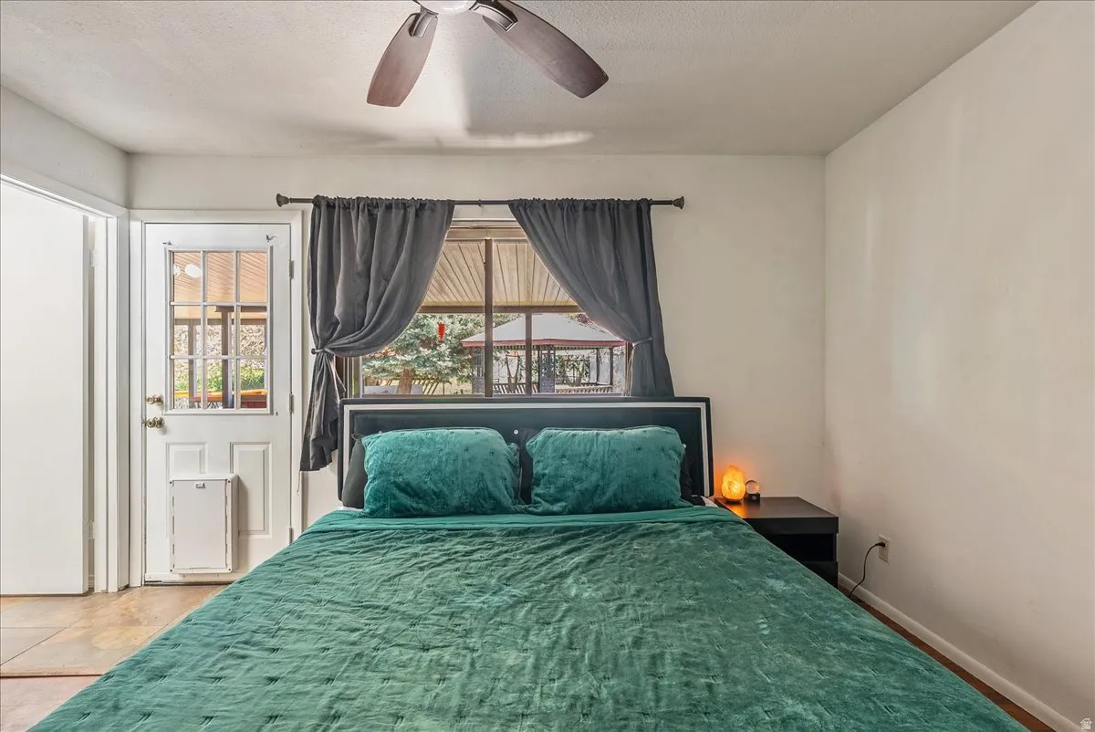 Bedroom featuring a ceiling fan, multiple windows, and a textured ceiling
