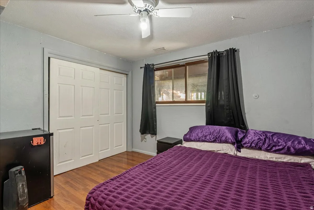 Bedroom featuring wood finished floors, a closet, a textured ceiling, ceiling fan