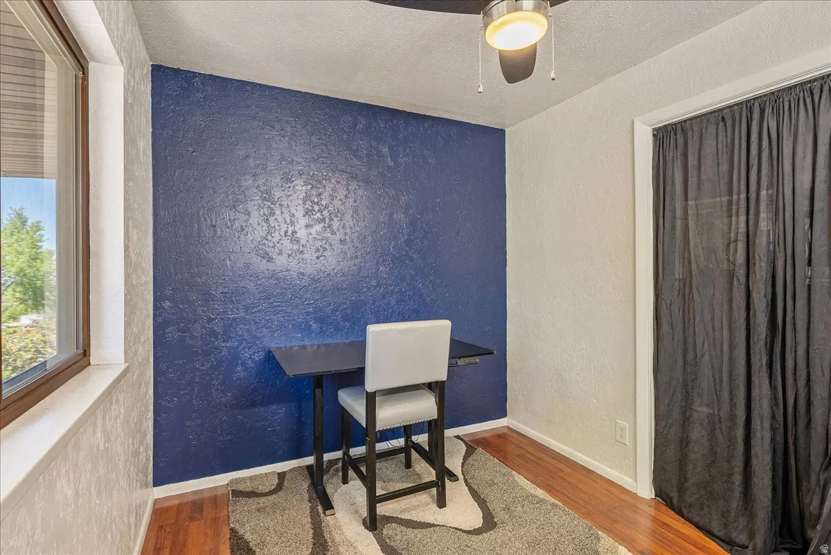 Office space with a textured wall, wood finished floors, a textured ceiling, and ceiling fan