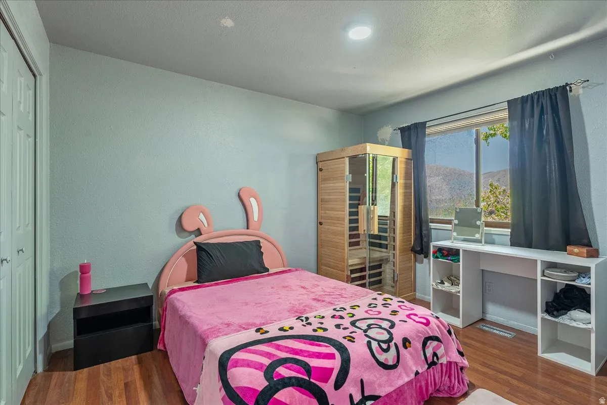 Bedroom featuring a relaxing sauna, a closet, wood finished floors, and a textured ceiling