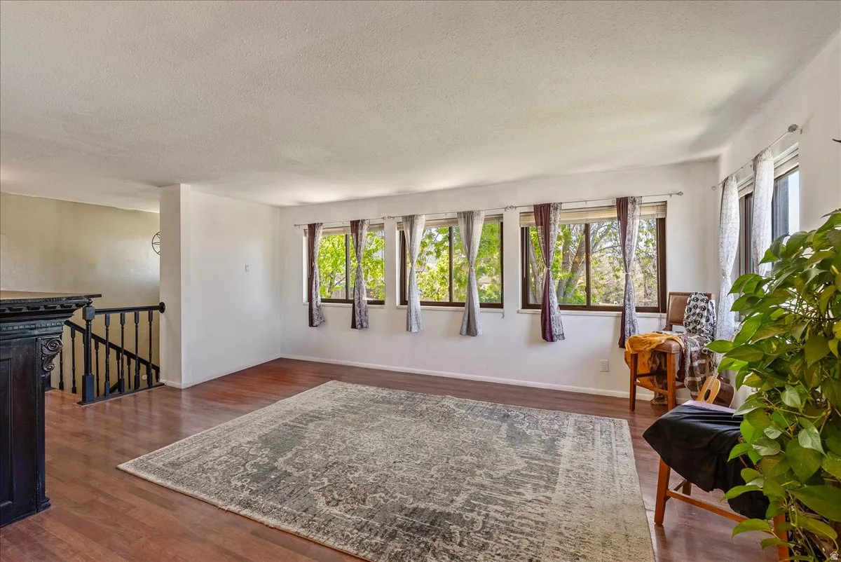 Sitting room featuring a textured ceiling, dark wood-style floors, and an upstairs landing