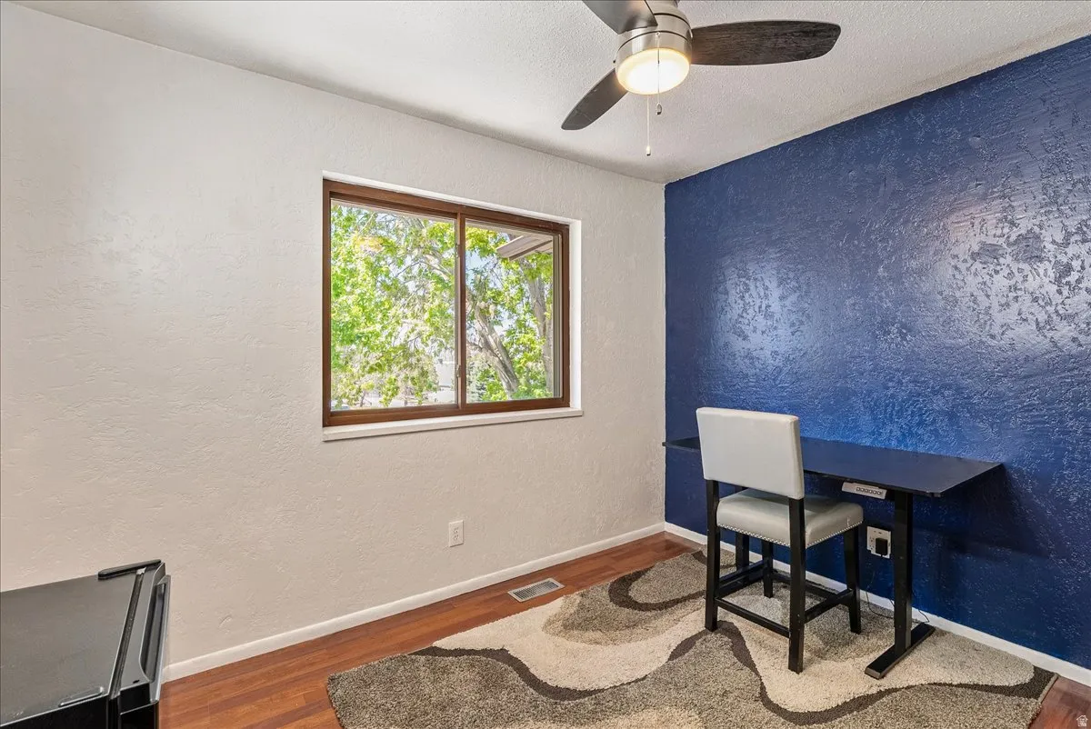 Office space with a textured wall, wood finished floors, a ceiling fan, and a textured ceiling
